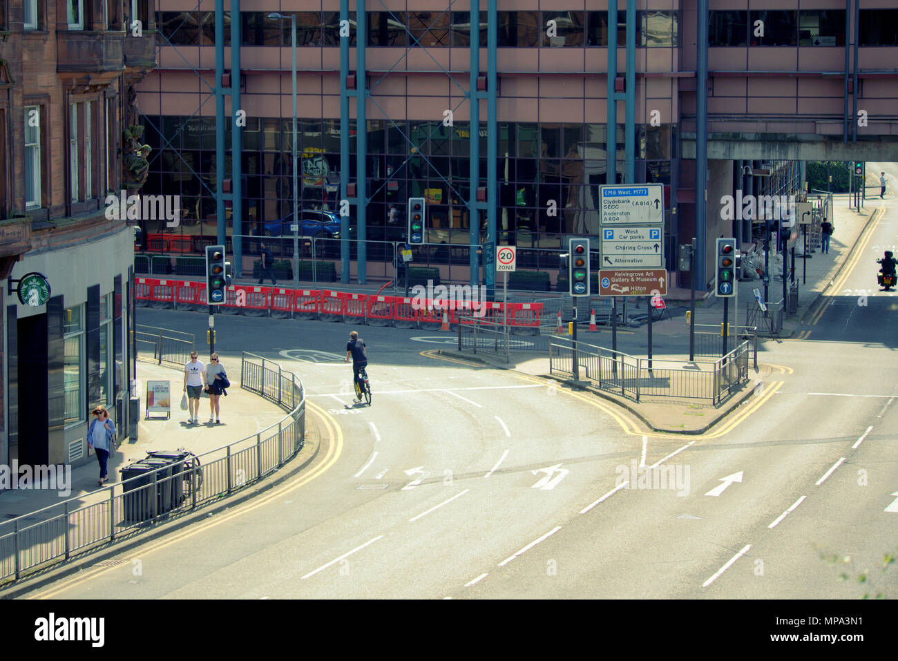 lone cyclist at empty street busy city centre Crossroads no cars Charing Cross, Glasgow, UK Stock Photo