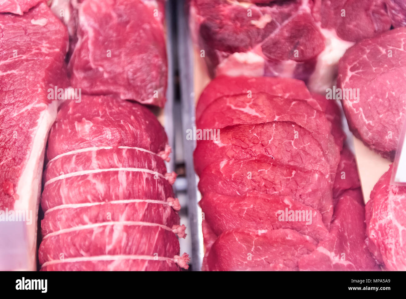 Dark red raw fatty meat boneless with fat beef steaks and roast, in store display for sale closeup Stock Photo