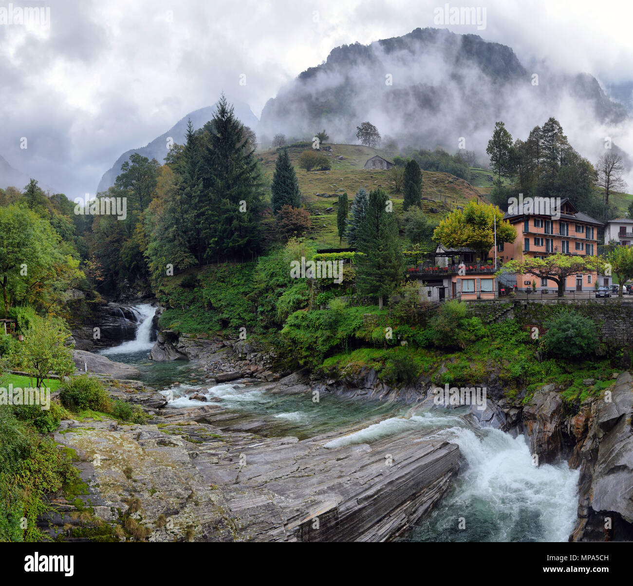 Swiss village in the mountains with mist and waterfall Stock Photo