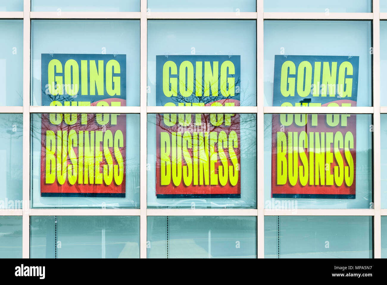 Closeup of yellow store closing banner poster sign on glass window of store building for bankruptcy going out of business Stock Photo