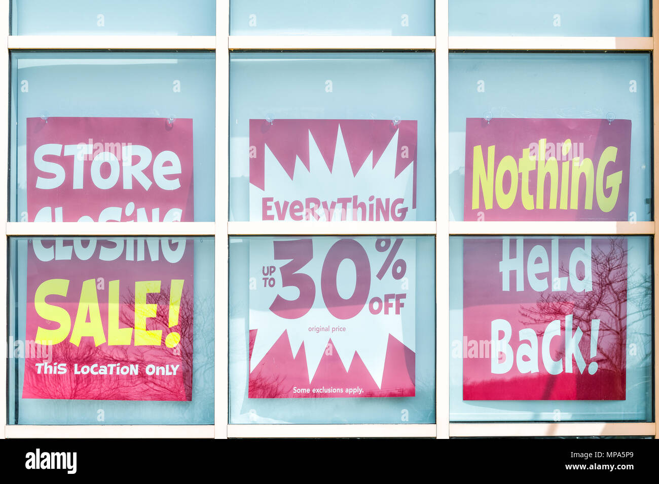 Closeup of red and yellow store closing banner poster sign on glass window of store building for bankruptcy going out of business Stock Photo