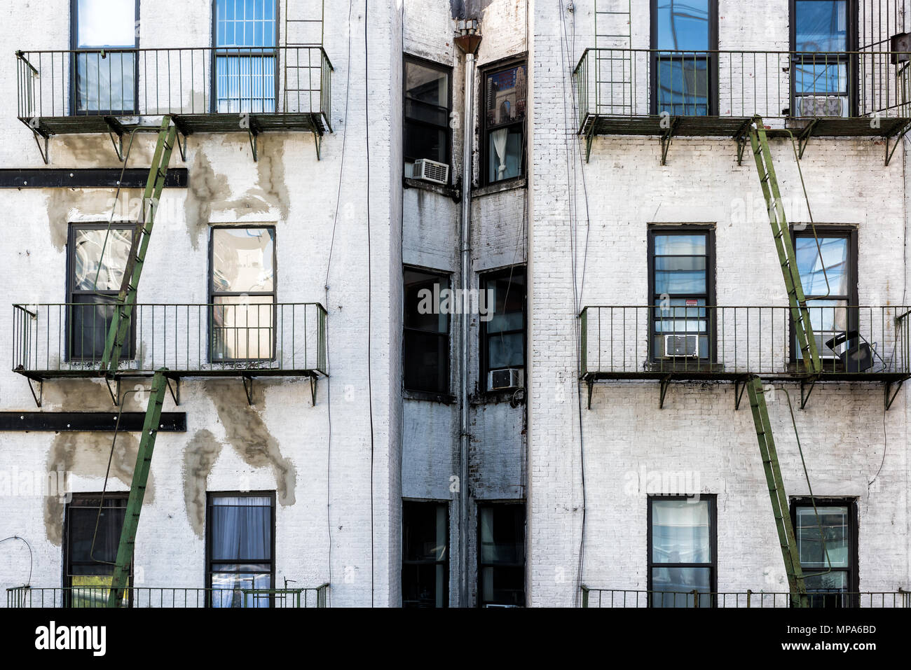 Old apartment condo building exterior architecture in Chelsea, NYC, Manhattan, New York City with fire escapes, windows, green ladders Stock Photo