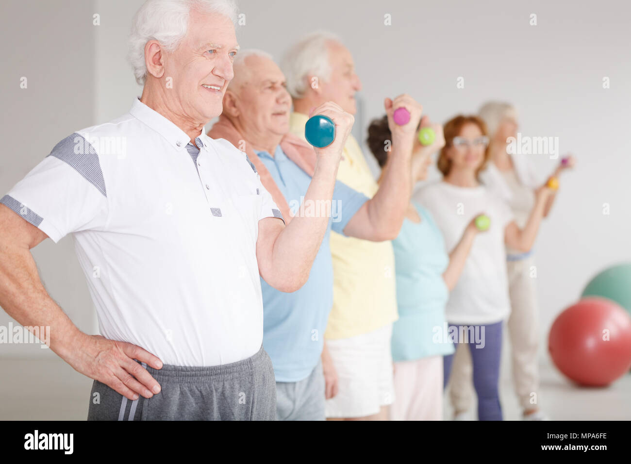Group of active seniors using dumbbells during sport classes Stock Photo