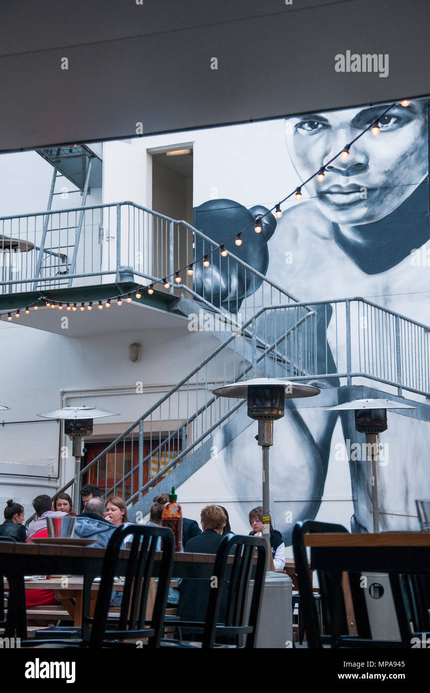 Diners seated beneath a Muhammad Ali mural in Fish Lane, South Brisbane, Queensland, Australia Stock Photo