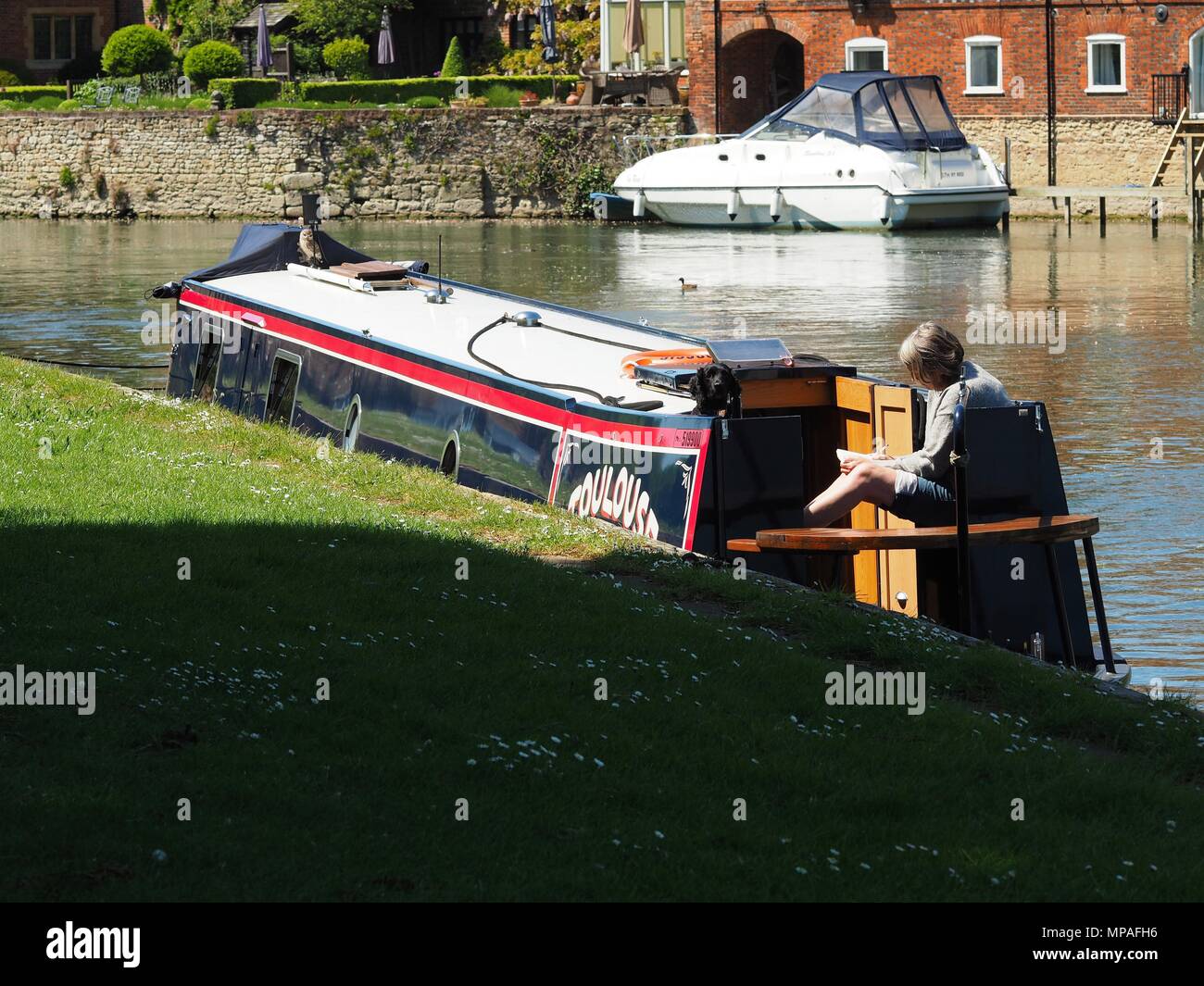 Lady Reads while sitting on a moored narrow boat in Abingdon Oxfordshire Stock Photo