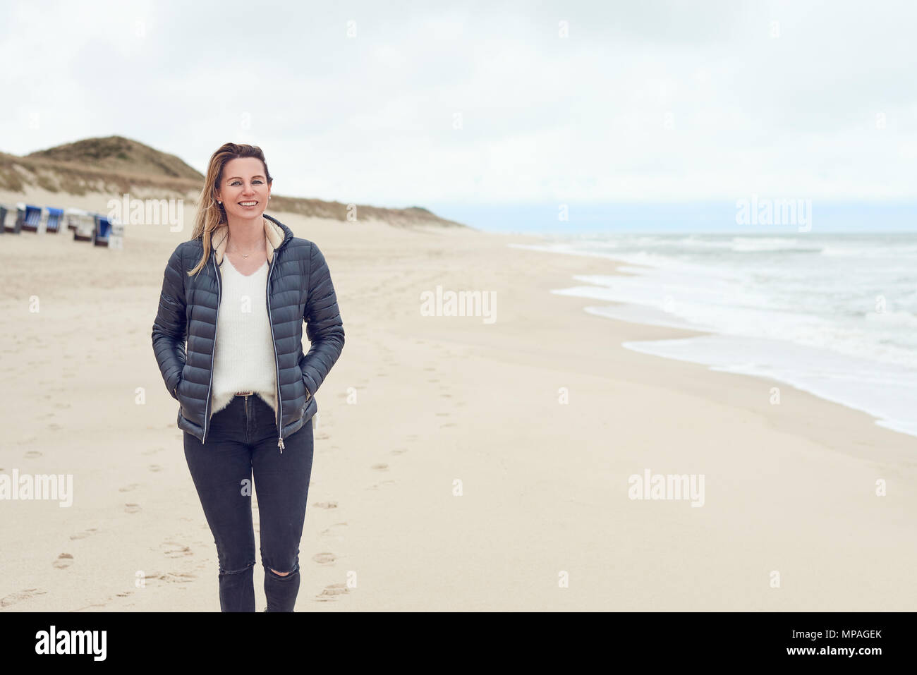 Woman walking on a beach on a cloudy day Stock Photo
