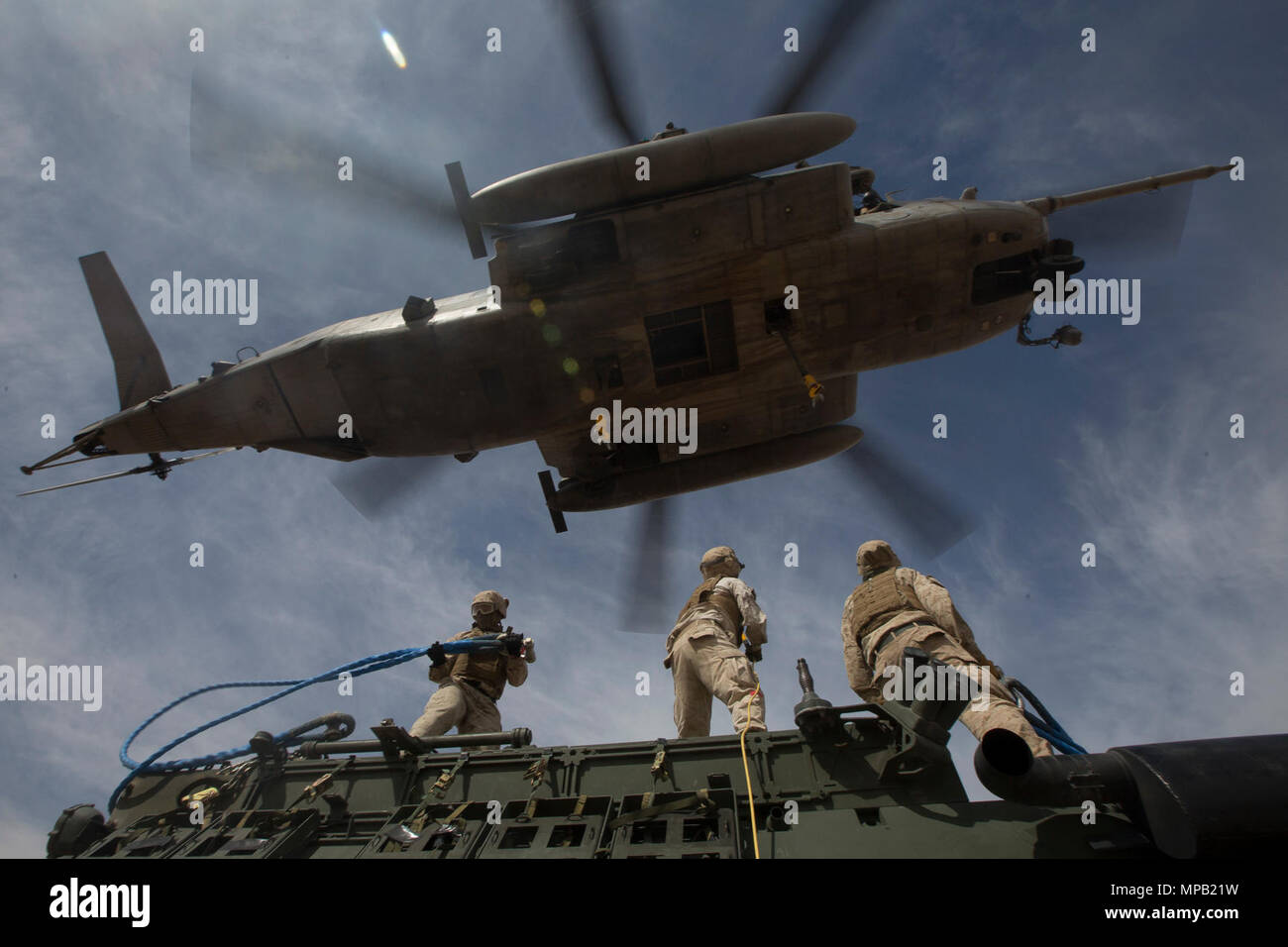 From left to right, U.S. Marine Corps Cpl. Tremayne O. Stinnett, Lance Cpl. Michael J. Mitchell, and Lance Cpl. Erick Alvarado, landing support specialists, with 1st Transportation Support Batallion, attach while a Light Armored Vehicle 25 to a CH-53E Super Stallion during a CH-53 tactics exercise at Auxiliary Airfield II, Yuma, Ariz., April 7, 2017. The exercise is part of Weapons and Tactics Instructor Course (WTI) 2-17, a seven-week training event hosted by Marine Aviation Weapons and Tactics Squadron One (MAWTS-1) cadre. MAWTS-1 provides standardized tactical training and certification of  Stock Photo