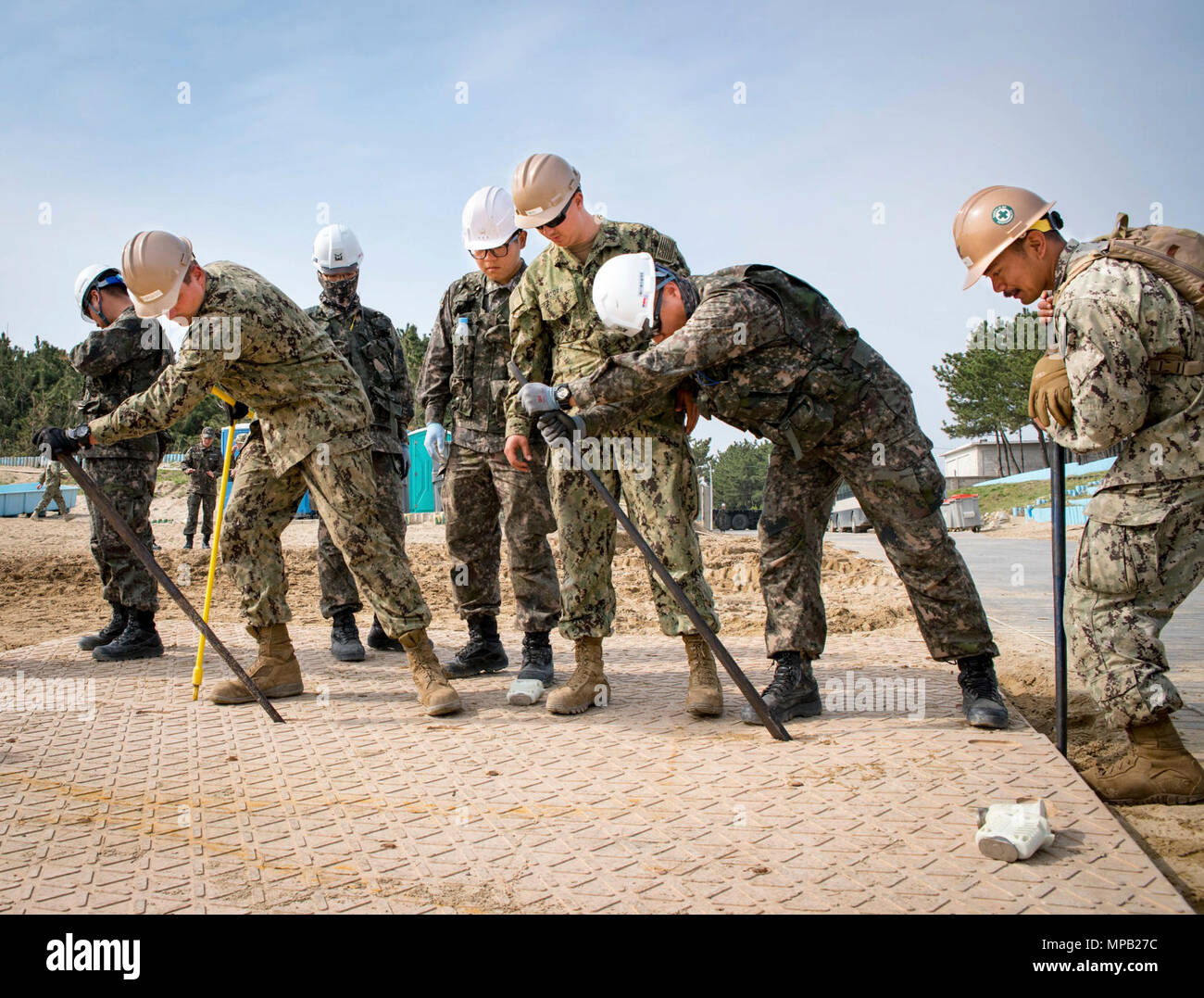 POHANG, Republic of Korea (April 8, 2017) – Seabees, attached to Amphibious Construction Battalion 1, and ROK Seabees, attached to Naval Mobile Construction Battalion 1, Naval Mobile Construction Squadron 53, align sections of durable matting during Operation Pacific Reach Exercise 2017 (OPRex17). OPRex17 is a bilateral training event designed to ensure readiness and sustain the ROK-U.S. Alliance by exercising an Area Distribution Center (ADC), an Air Terminal Supply Point (ATSP), Combined Joint Logistics Over-the-Shore (CJLOTS), and the use of rail, inland waterways, and coastal lift operatio Stock Photo