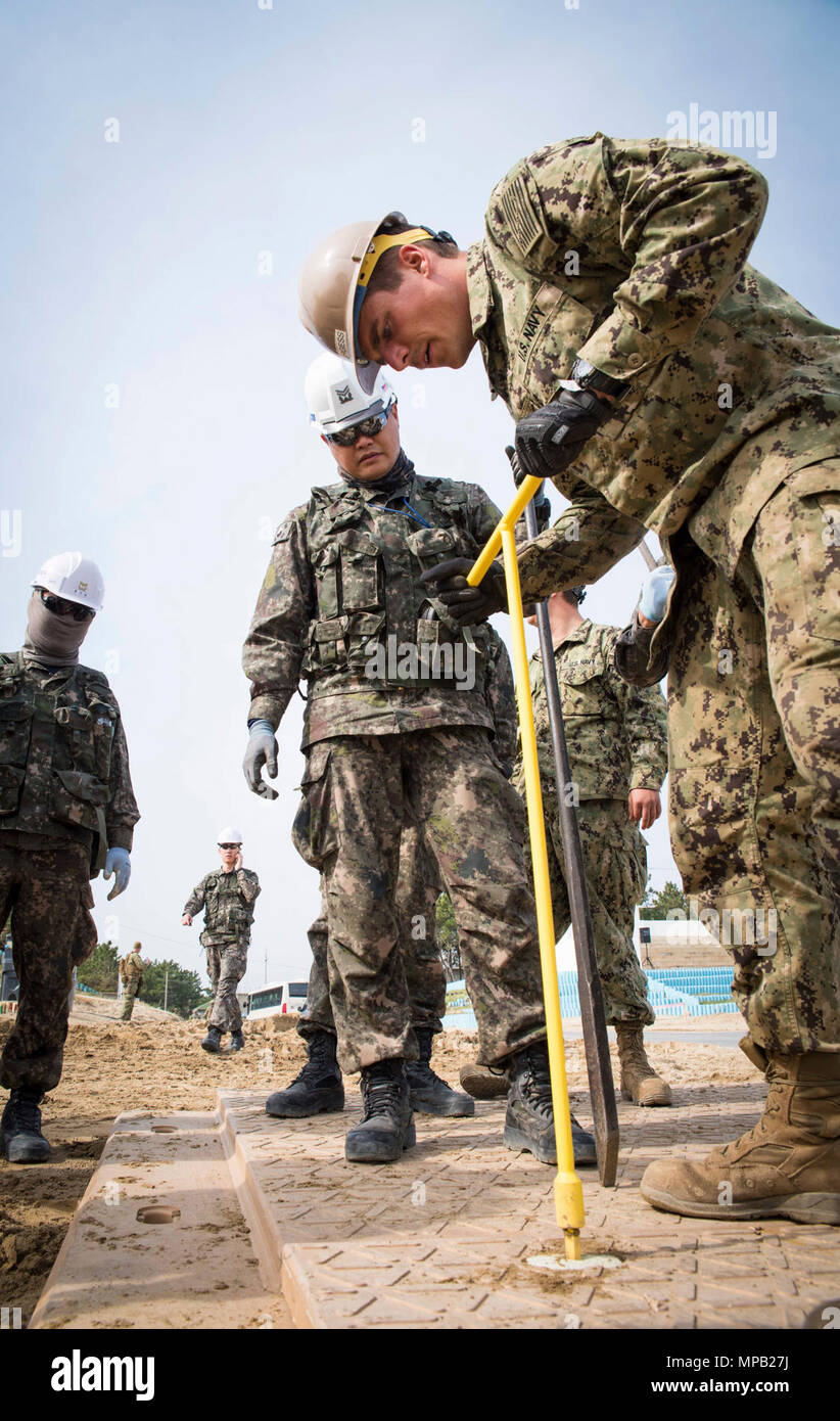 POHANG, Republic of Korea (April 8, 2017) – Seabees, attached to Amphibious Construction Battalion 1, and ROK Seabees, attached to Naval Mobile Construction Battalion 1, Naval Mobile Construction Squadron 53, secure  sections of durable matting into position during Operation Pacific Reach Exercise 2017 (OPRex17). OPRex17 is a bilateral training event designed to ensure readiness and sustain the ROK-U.S. Alliance by exercising an Area Distribution Center (ADC), an Air Terminal Supply Point (ATSP), Combined Joint Logistics Over-the-Shore (CJLOTS), and the use of rail, inland waterways, and coast Stock Photo