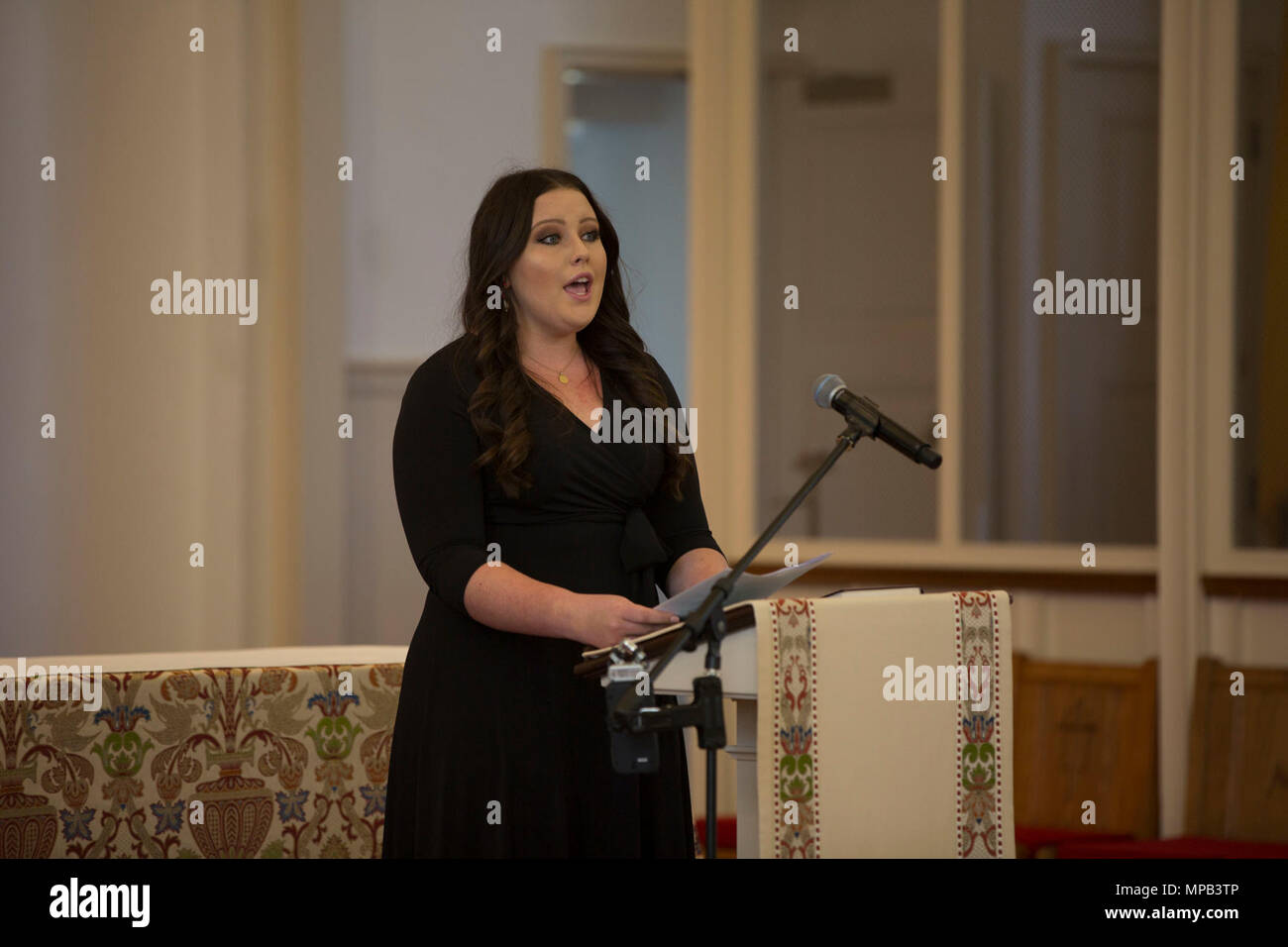 Kailee Kakazu, granddaughter of retired U.S. Marine Corps Lt. Gen. Lawrence F. Snowden, sings during her grandfather’s memorial service at the U.S. Marine Memorial Chapel, Quantico, Va., April 8, 2017. His father retired in 1979 after nearly 40 years of service, fought in engagements during World War II, the Korean War, and Vietnam. He passed away Feb. 18, 2017. He was prominently known after retirement for organizing joint 'Reunion of Honor' missions which is an opportunity for Japanese and U.S. veterans and their families, dignitaries, leaders and service members from both nations to come to Stock Photo