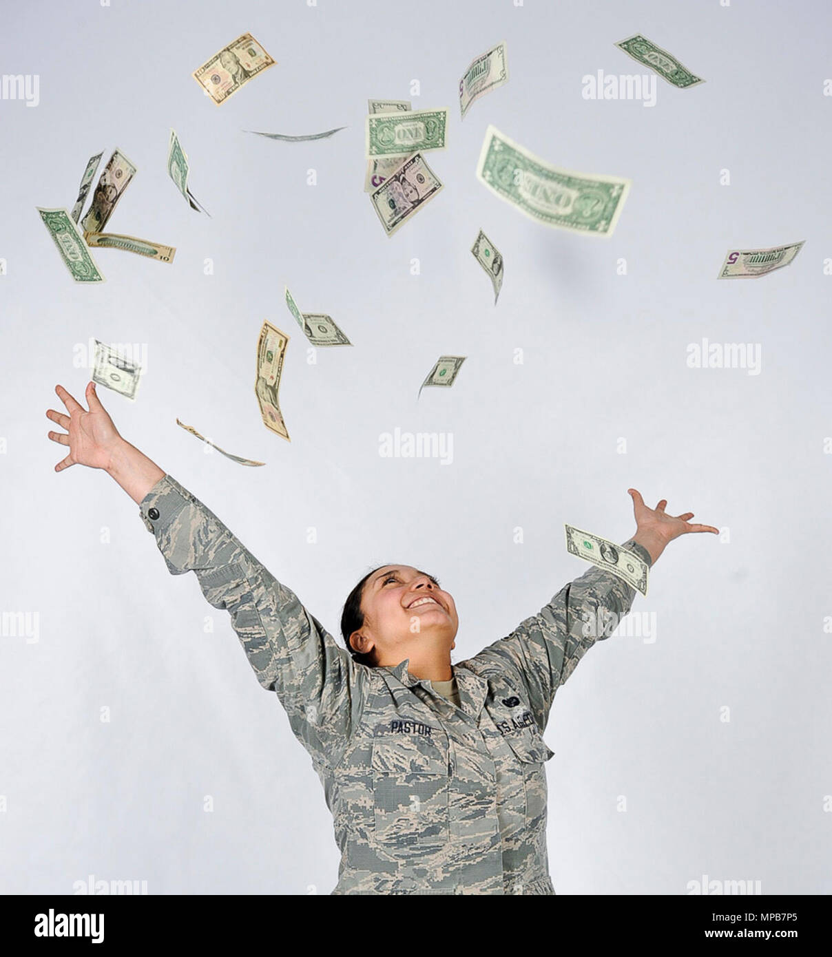 Airman 1st Class Daniela Pastor, 86th Airlift Wing Judge Advocate paralegal, throws money into the air on Ramstein Air Base, April 7, 2017. Beginning in 2018, service members have the opportunity to opt-into a new Blended Retirement System, and can get automatic and matching Thrift Savings Plan contributions as well as mid-career compensation incentives in addition to a monthly annuity for life. Stock Photo