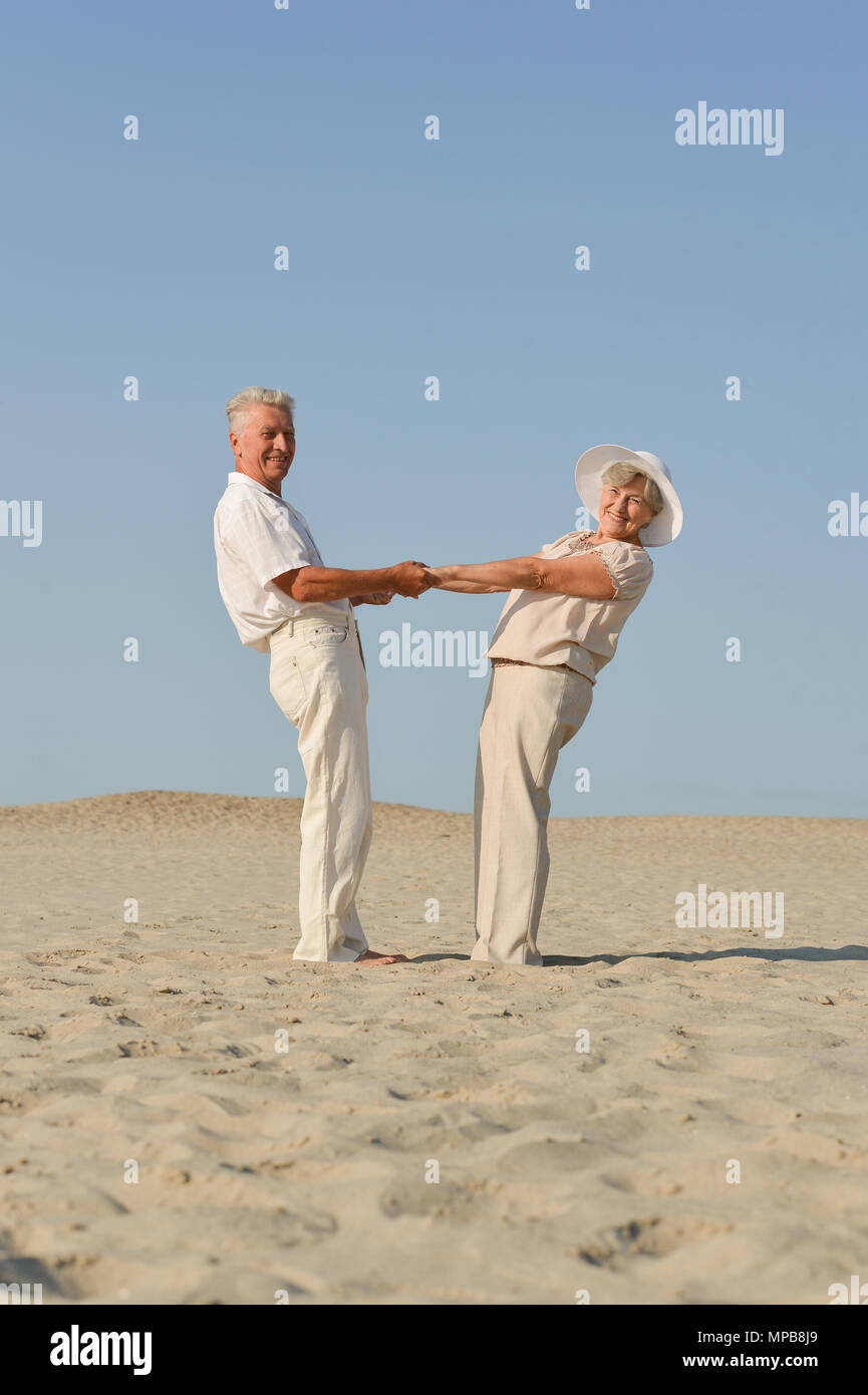 old couple in love walking barefoot in the sand Stock Photo