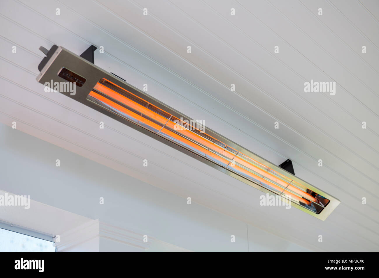An electric infrared heater on a screened in porch provides radiant heat  on cool days Stock Photo