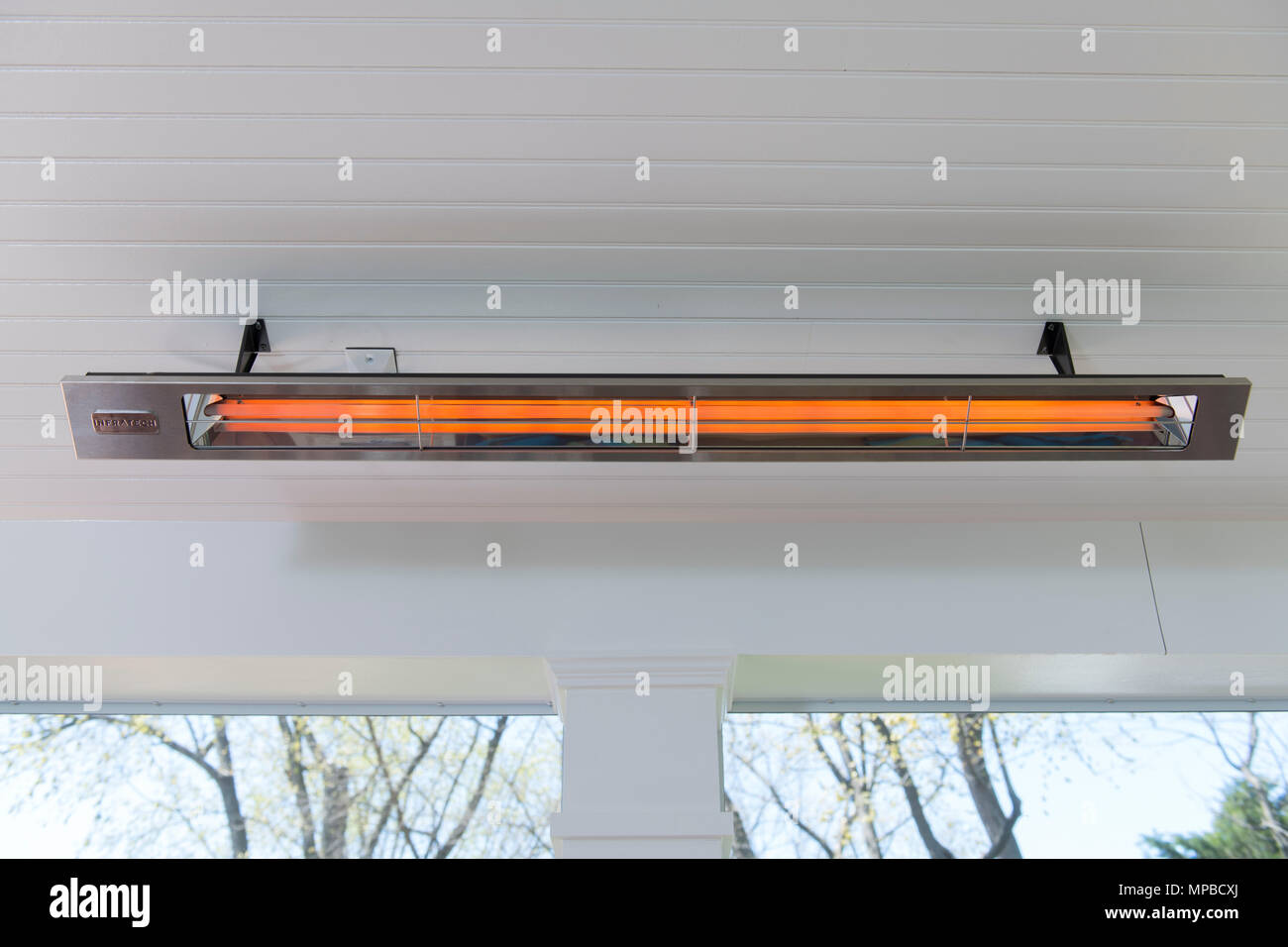 An electric infrared heater on a screened in porch provides radiant heat  on cool days Stock Photo
