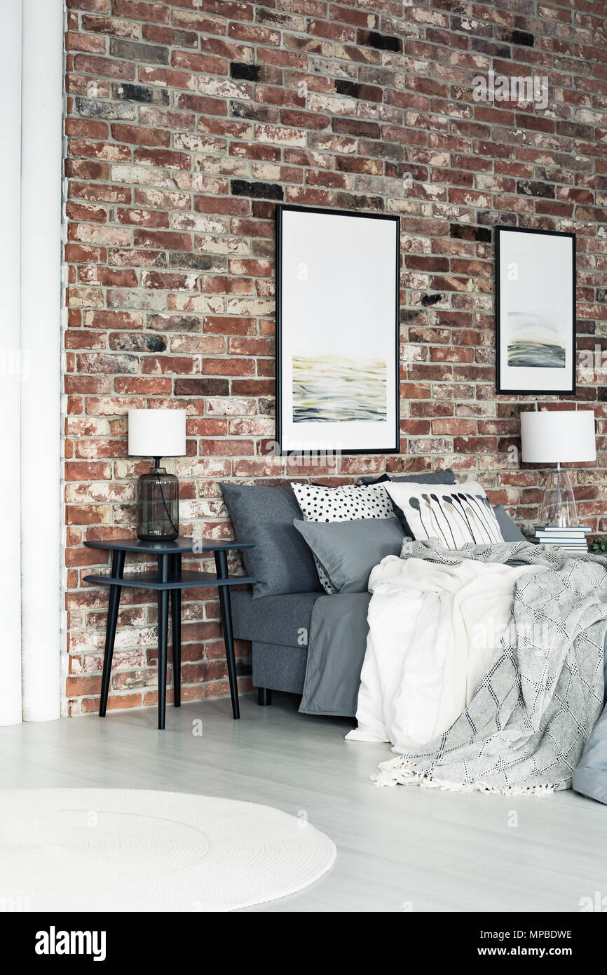 Two Posters Hanging On A Brick Wall In Loft Style Bedroom