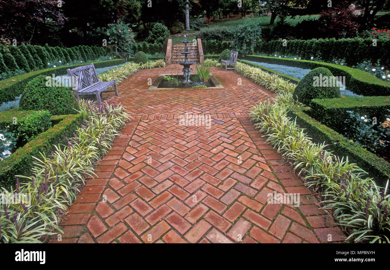 FORMAL GARDEN FEATURING WATER FEATURE, BRICK PAVING, LOW TRIMMED HEDGES AND PAVING EDGED WITH LOW GROWING PLANTS. MOUNT WILSON, NSW, AUSTRALIA. Stock Photo