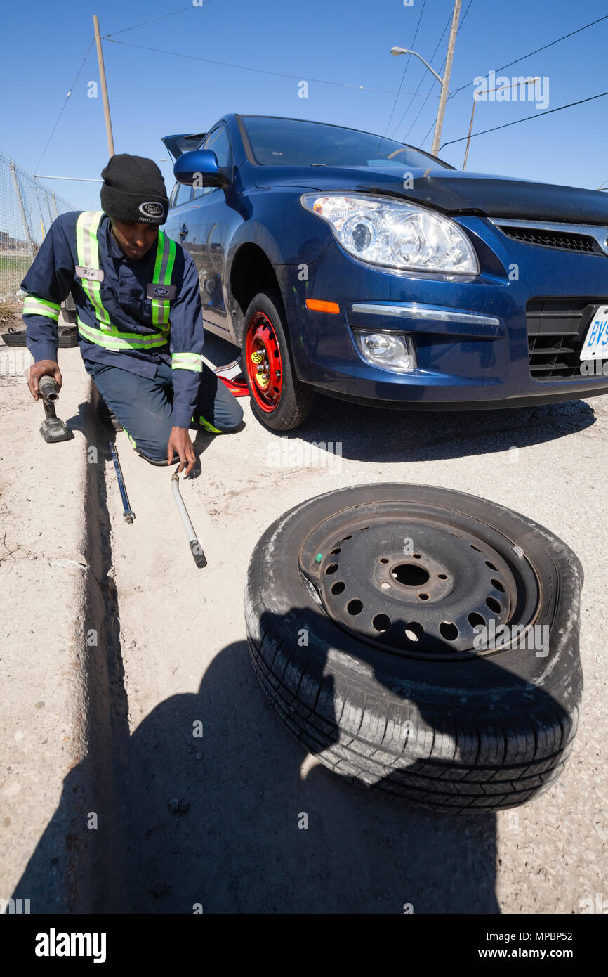 A service technician or person changing a flat tire or tyre. Stock Photo