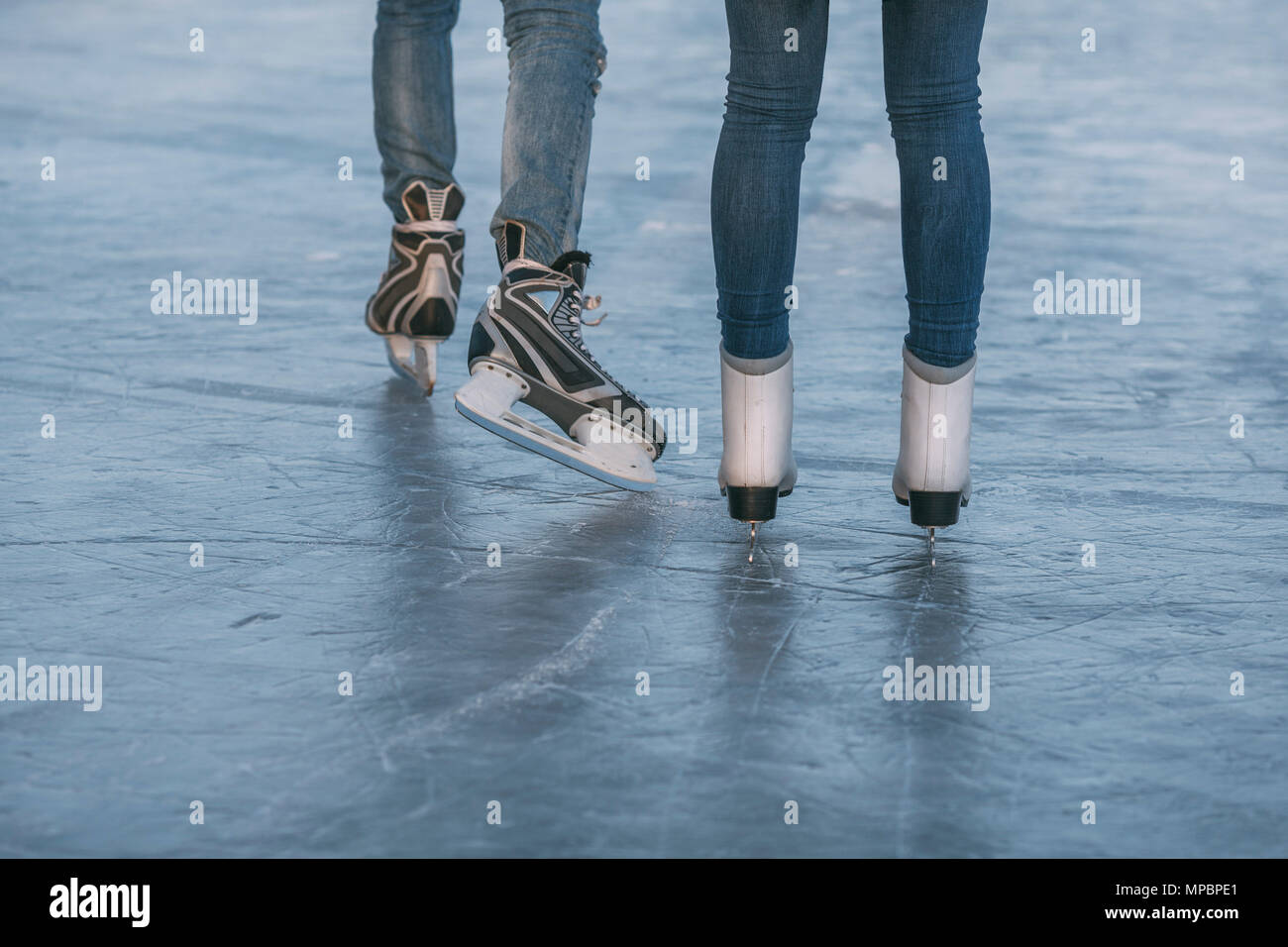Low section of couple ice-skating on rink Stock Photo