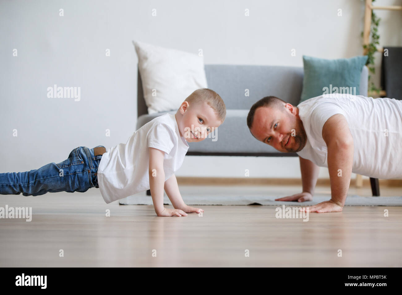 Image Of Young Father And Son Pushing Up On Floor Against Sofa