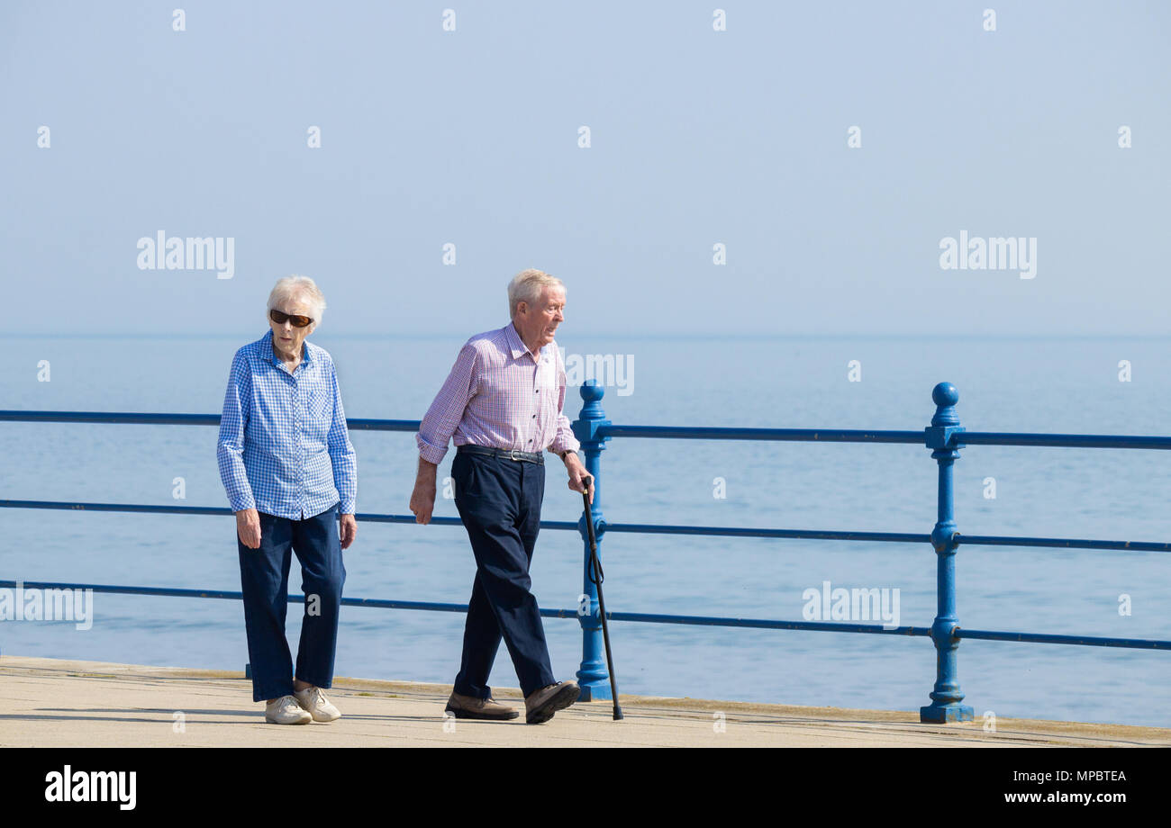 Elderly couple walking along seafron on sunny day. UK Stock Photo