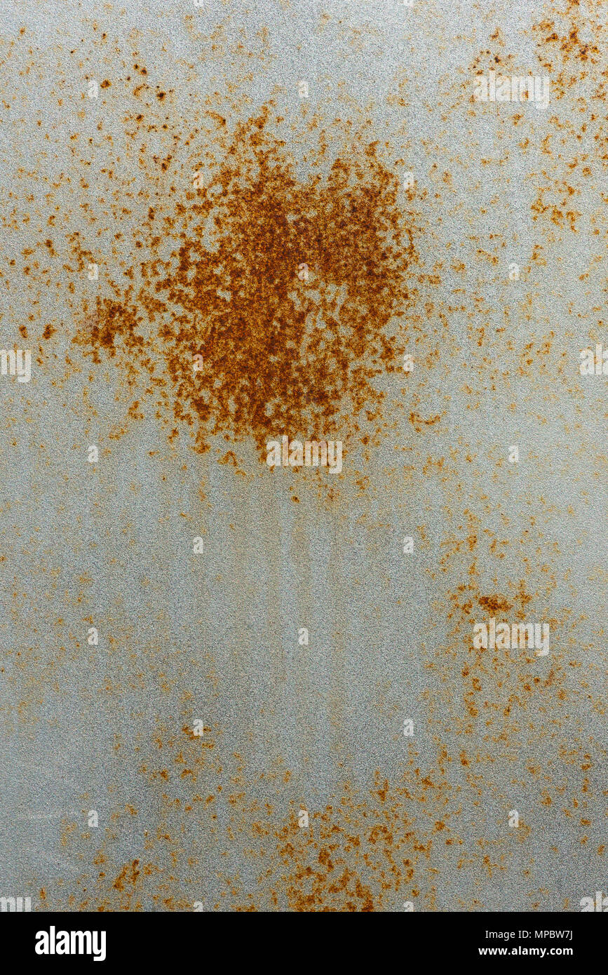 Weathered silver painted steel rusting with streaks of rust caused by