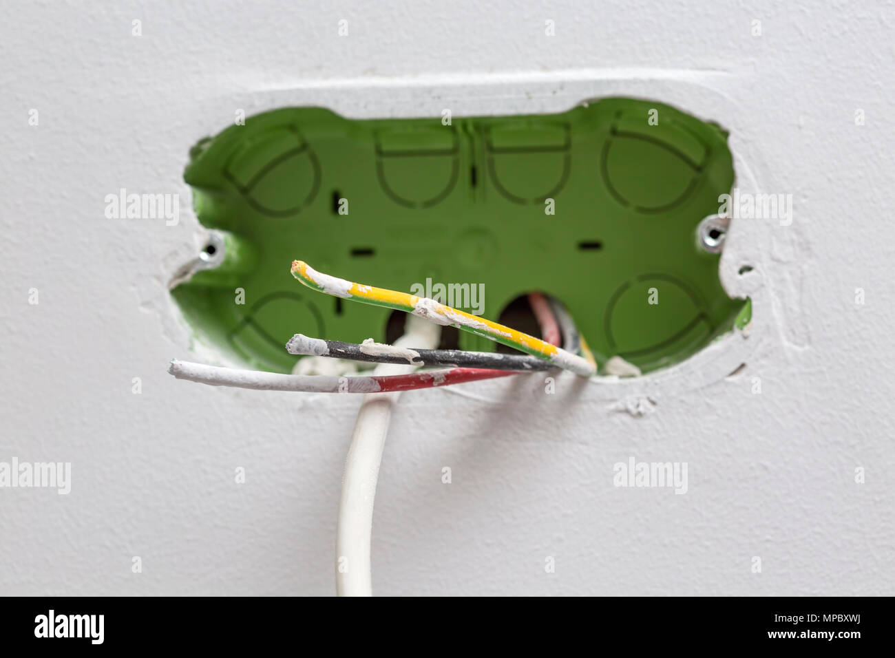 Unfinished electrical mains outlet socket with electrical wires and TV