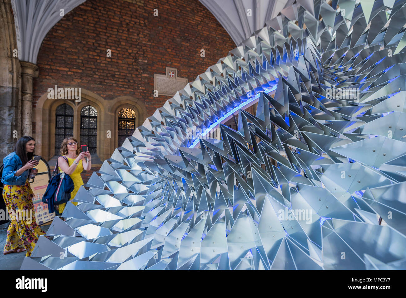 London, UK. 22nd May, 2018. Design bloggers tour the installations. Royal Approval the biggest Elizabethan ruff ever created - made from sheet aluminium folded in an origami way, it has been created by Kinetech Design in collaboration with Amari Interiors and Timberfusion. It is in St John's Gate which saw the first performances of some of Shakespeare's most famous works - Outdoor installations for Clerkenwell Design Week, which starts today. Credit: Guy Bell/Alamy Live News Stock Photo