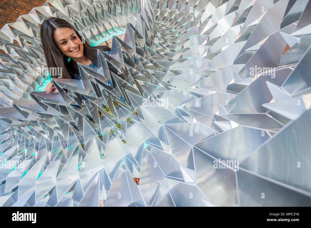 London, UK. 22nd May, 2018. Design bloggers tour the installations. Royal Approval the biggest Elizabethan ruff ever created - made from sheet aluminium folded in an origami way, it has been created by Kinetech Design in collaboration with Amari Interiors and Timberfusion. It is in St John's Gate which saw the first performances of some of Shakespeare's most famous works - Outdoor installations for Clerkenwell Design Week, which starts today. Credit: Guy Bell/Alamy Live News Stock Photo