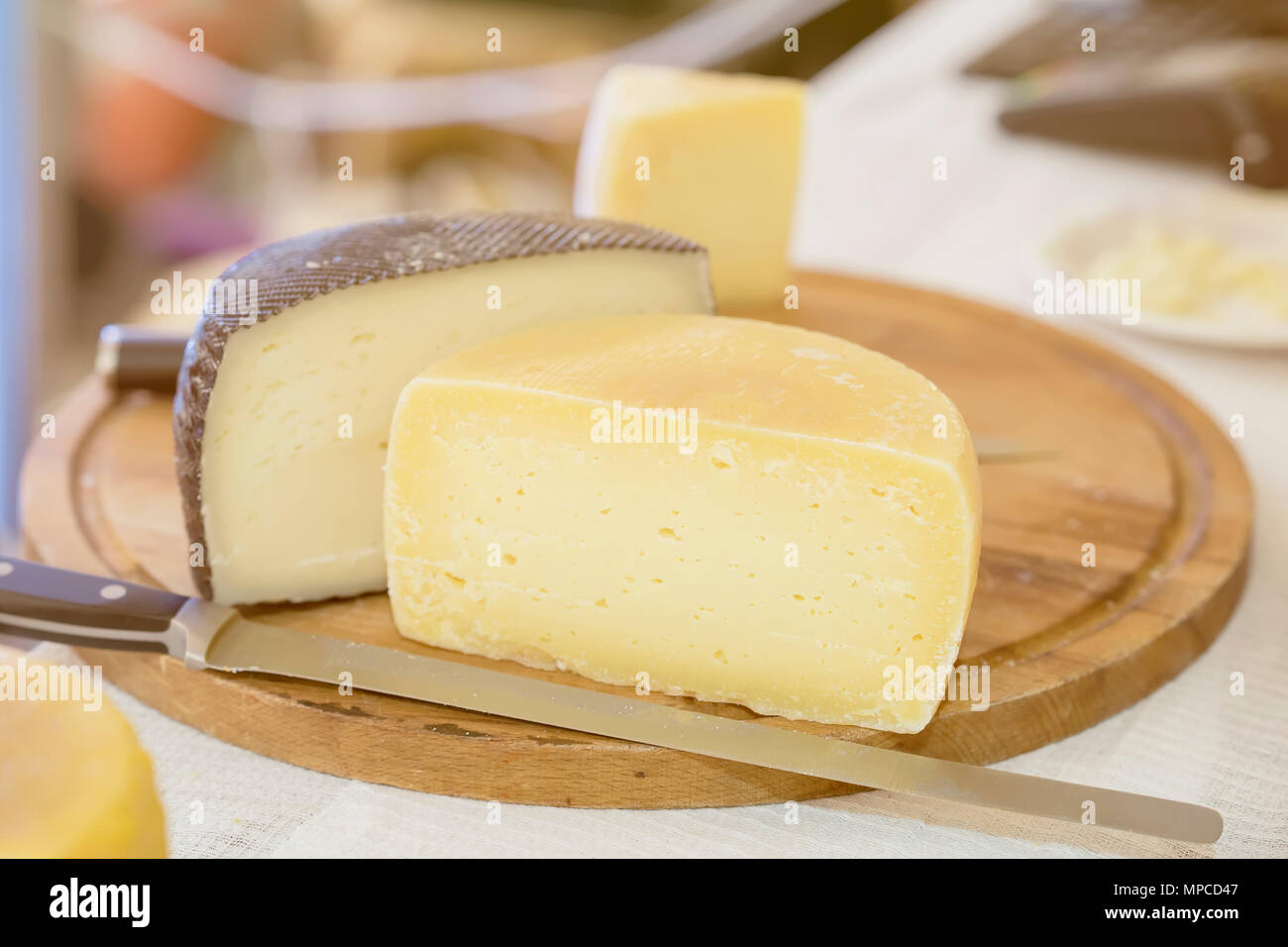 Halves hard cheese heads on wooden market board. Gastronomic dairy produce, real scene in the food market Stock Photo