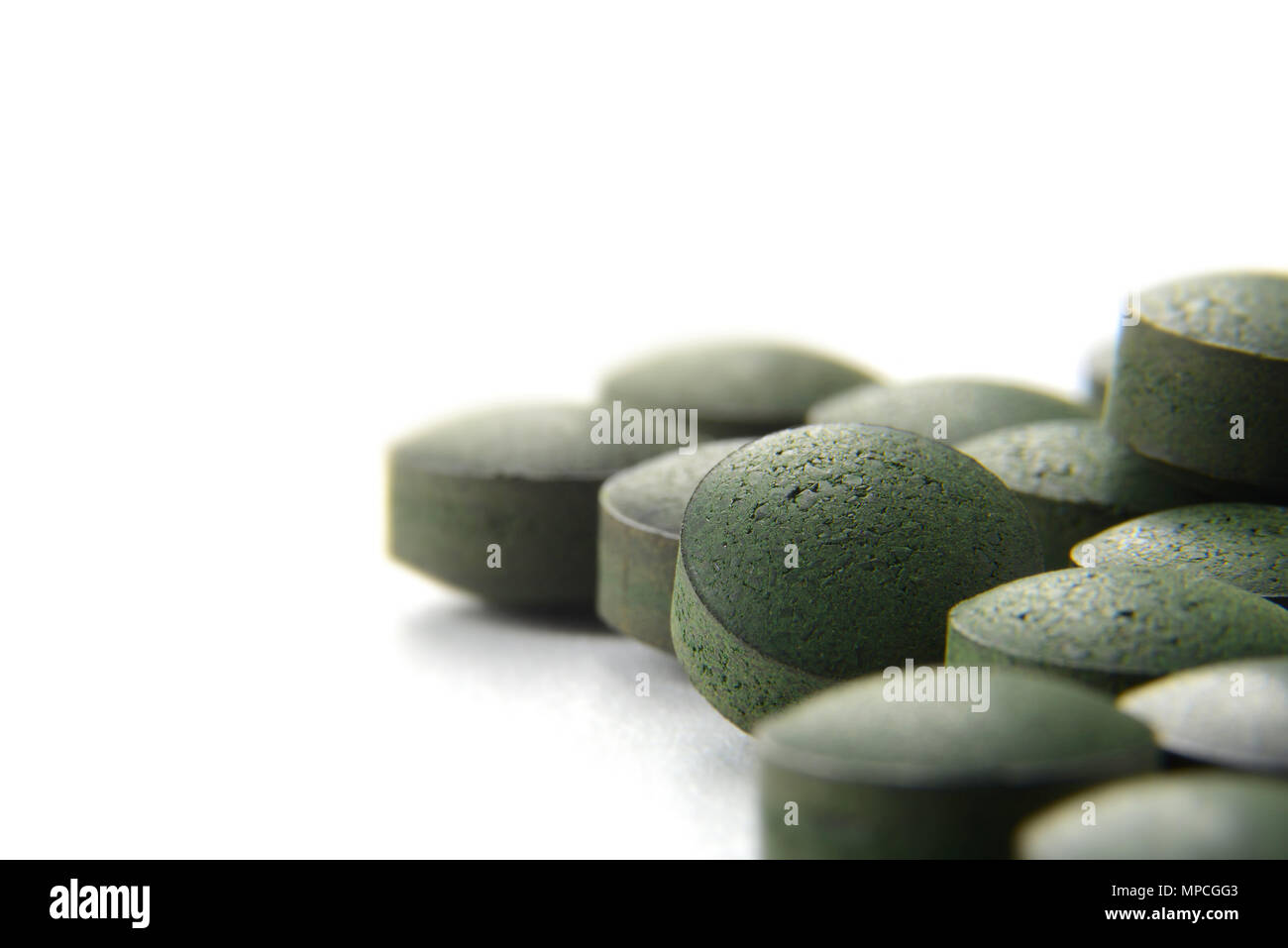 Close up of many organic spirulina tablets with low depth of field over white background. Stock Photo