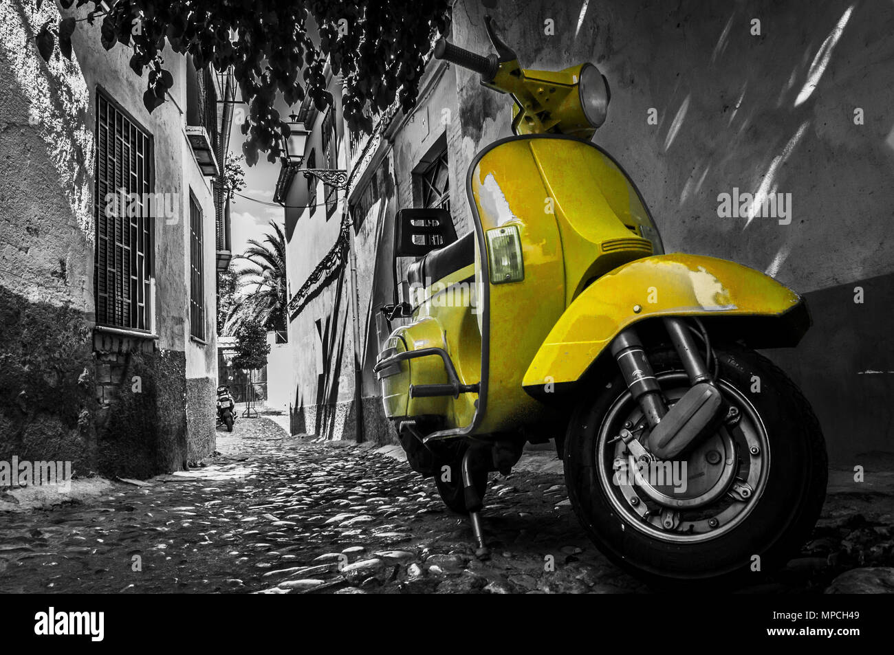 Yellow vespa scooter parked in an old empty paved street in Italy Stock Photo