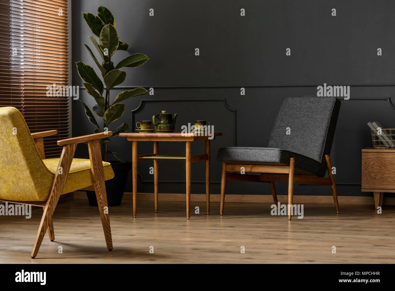 Simple, dark retro living room interior concept with two chairs, stool