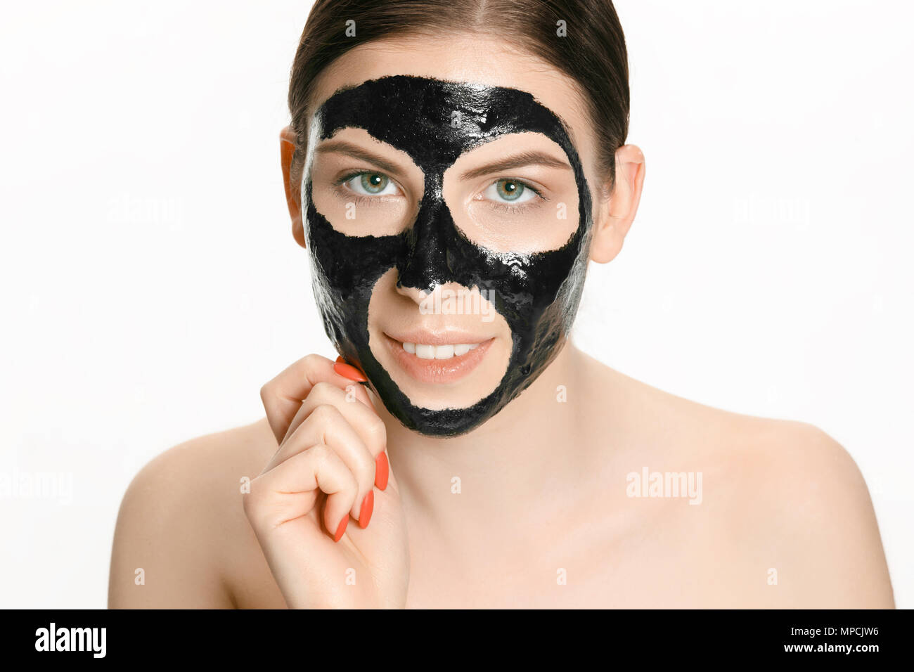 Young beautiful woman applying a mask for the face of the therapeutic black mud. Spa treatment Stock Photo