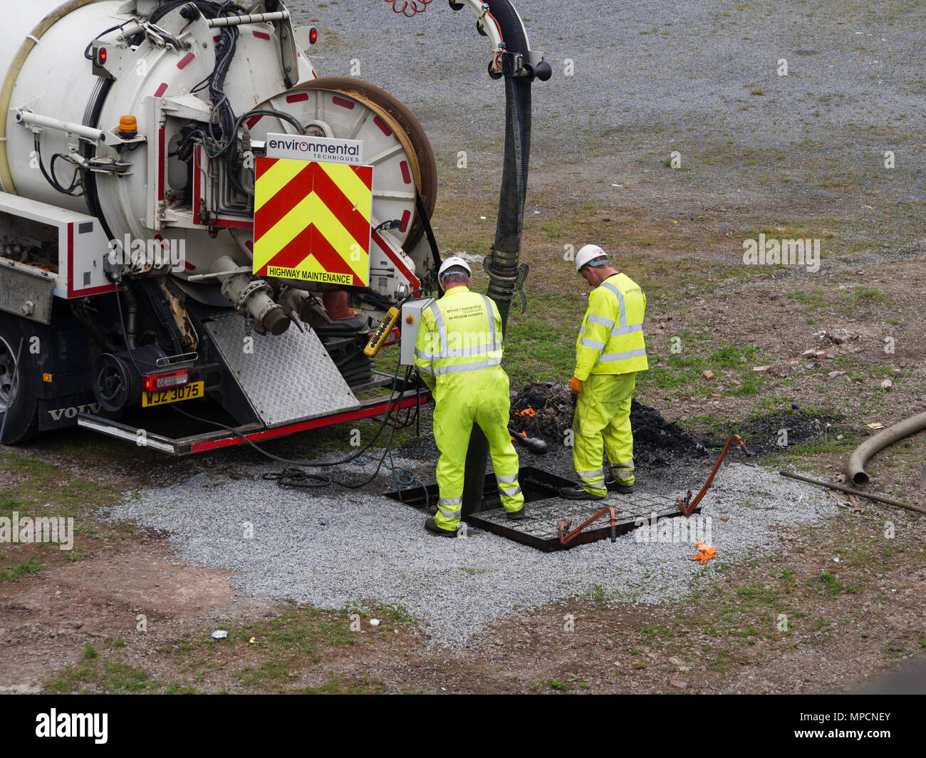 Workmen in high vis jackets operating equipment to clear drains Stock Photo
