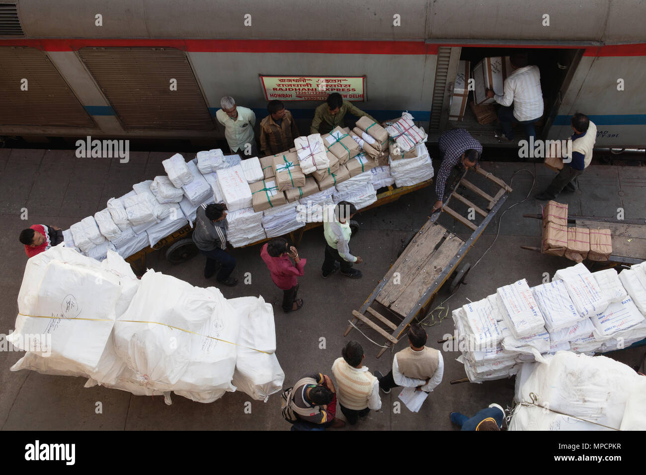 India, New Delhi, Porters loading baggage into the goods carriage of an