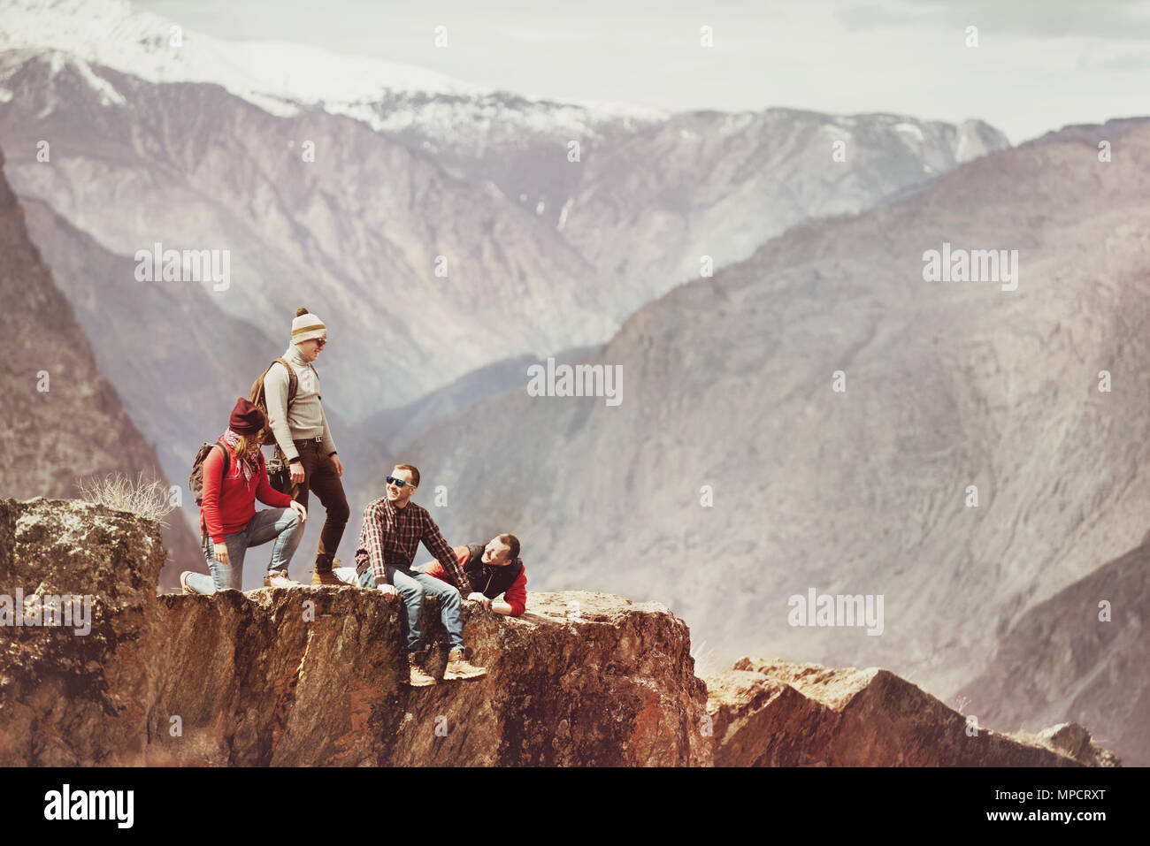 Group of tourists on cliff against mountains Stock Photo