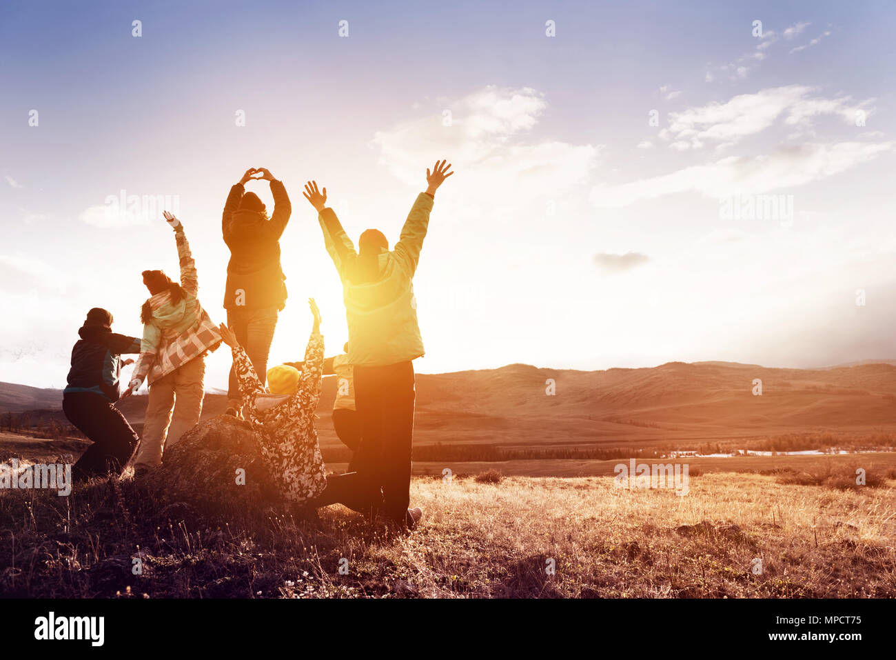 Happy tourists with raised arms against sunset Stock Photo