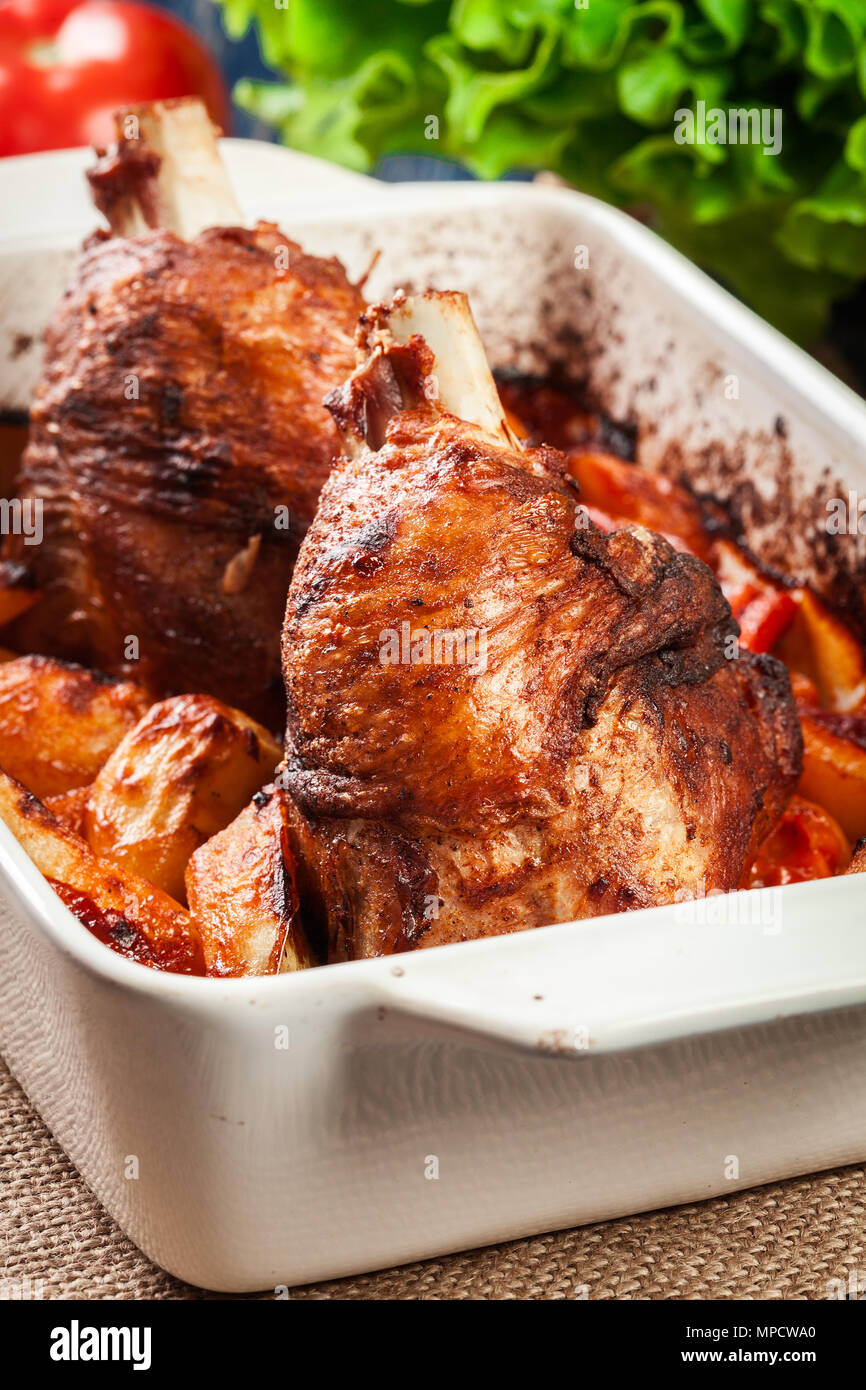 Roasted turkey knuckle with potatoes and vegetable in the baking dish
