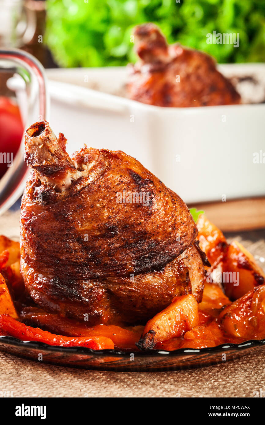 Roasted turkey knuckle with potatoes and vegetable on a plate Stock