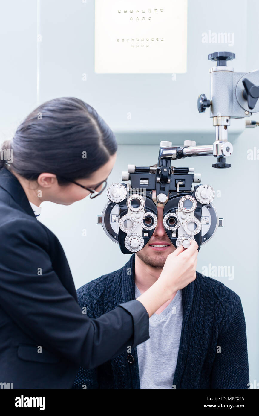 Optician and man at eye examination with phoropter Stock Photo