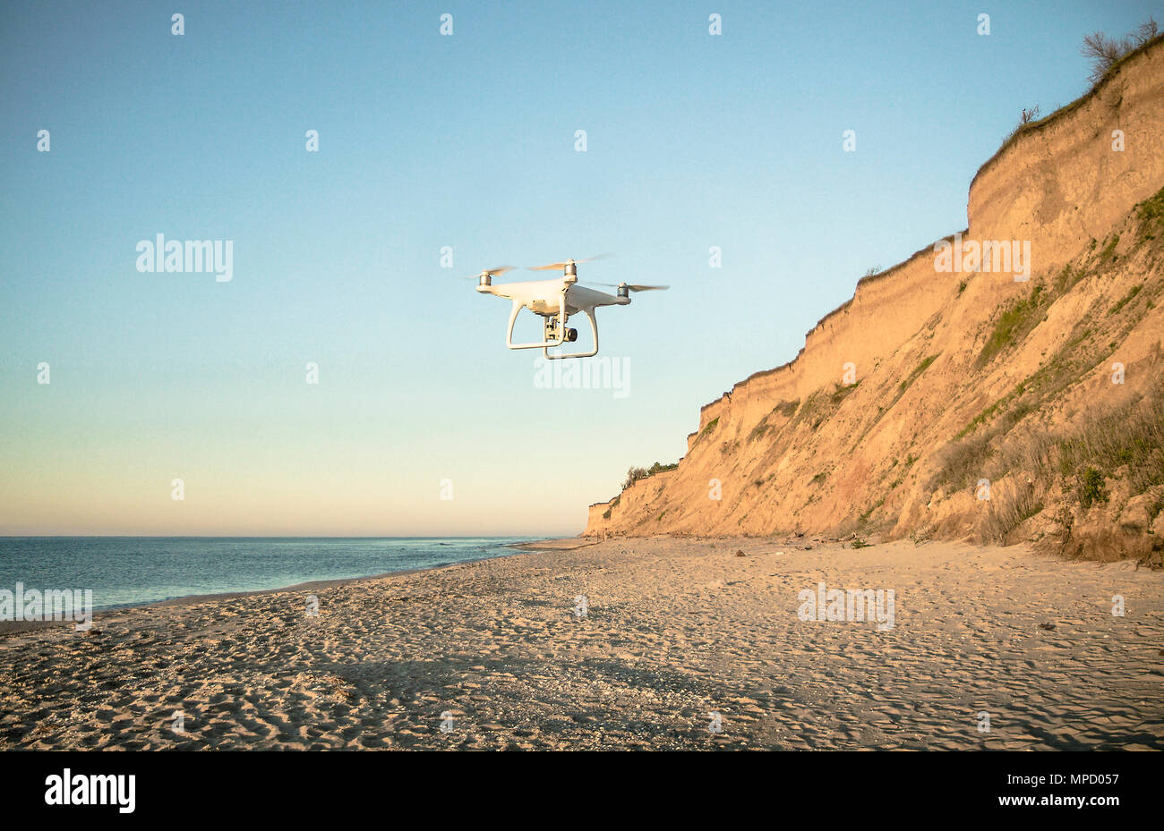 Drone flying over deserted fairy tale beach with golden sand and blue water on the shores of ocean. Romantic place near the sea. Cloudy day. Stock Photo