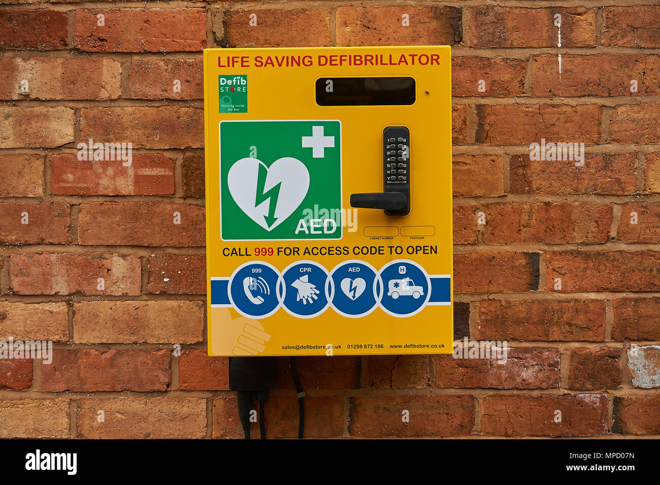 Yellow life saving defibrillator box mounted on the wall of a building Stock Photo
