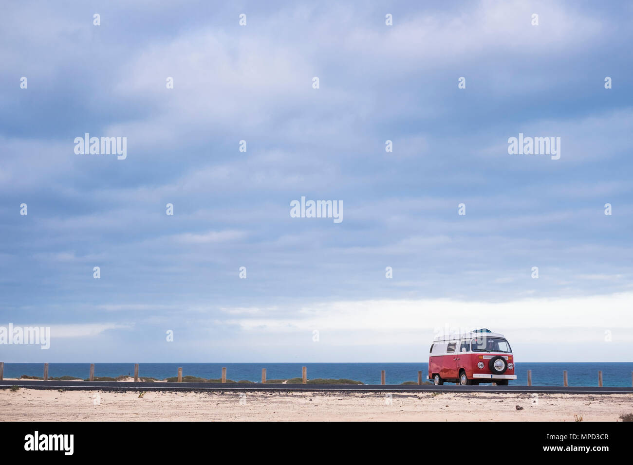 A red old vintage van parked for camping between sand and beach with ...