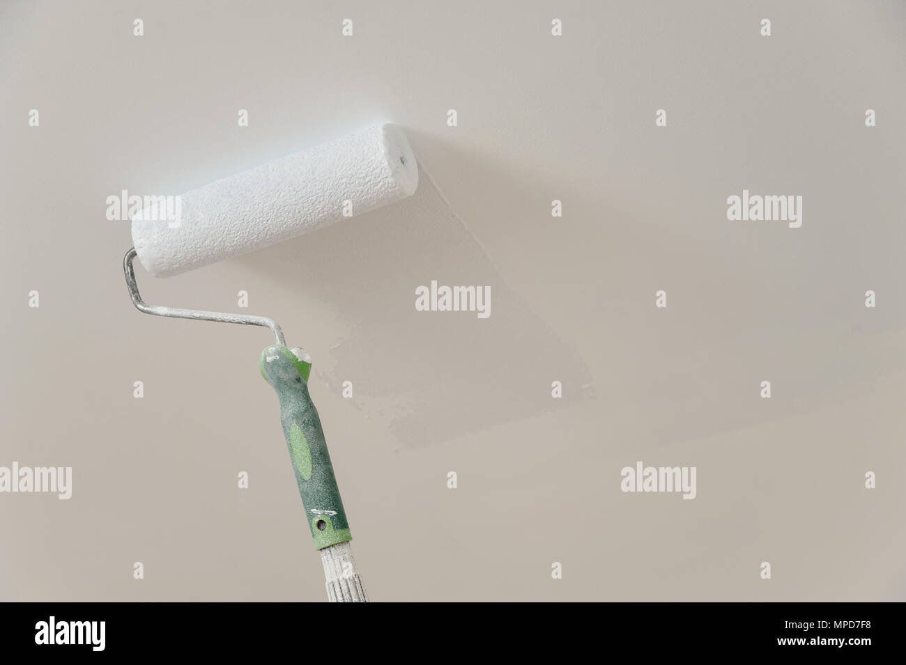 Painting the ceiling and walls. Roller touching the surface and leaving ...