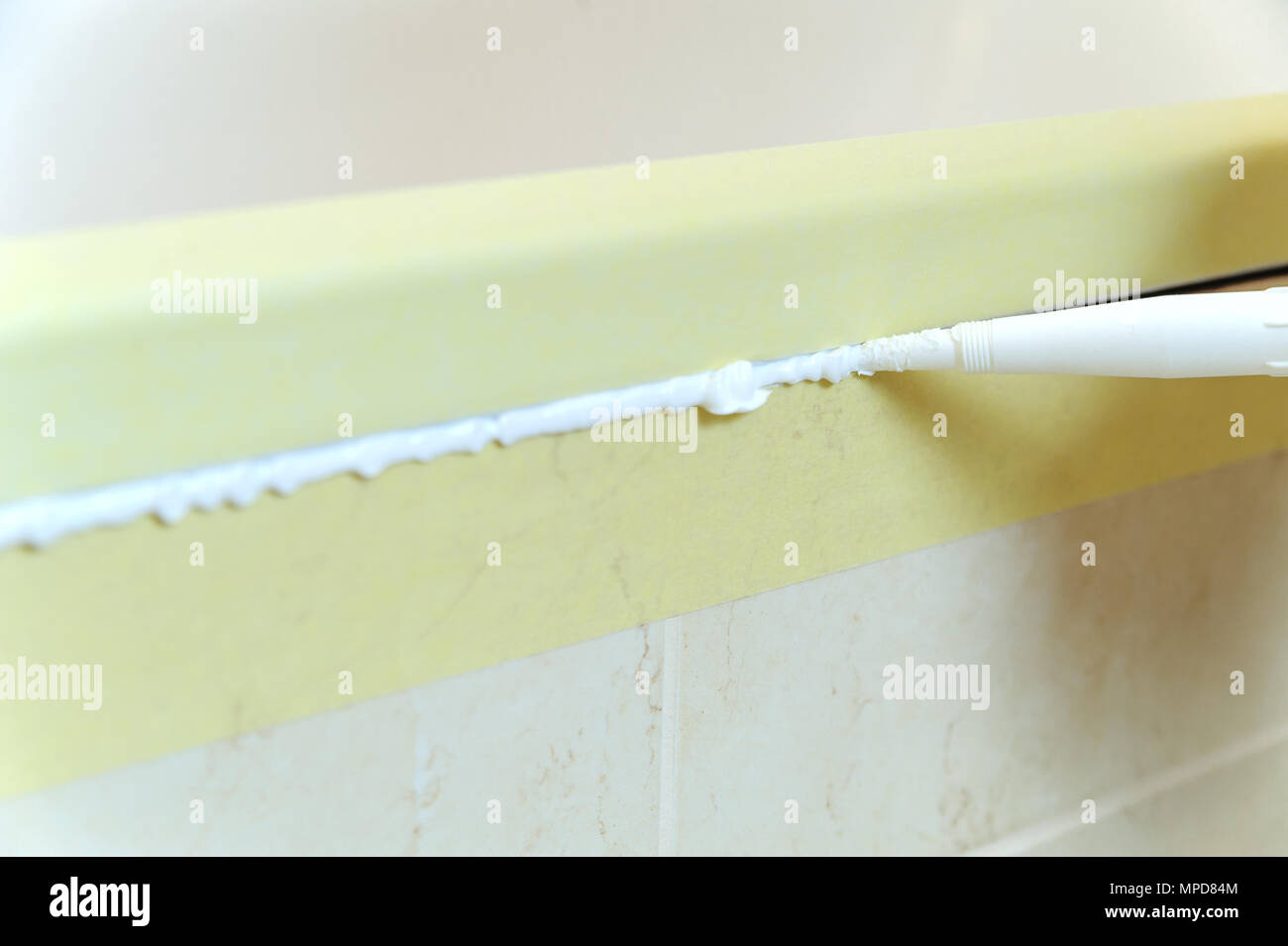 Worker puts silicone sealant to caulk the joint between tub and wall