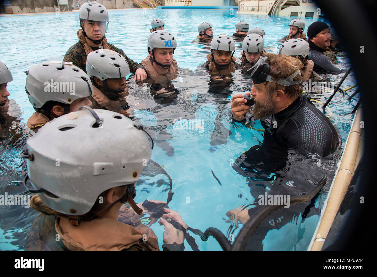 Jason Comeaux, Underwater Egress Training instructor, right, demonstrates how to breathe through an air regulator during UET on Camp Hansen, Okinawa, Japan, Feb. 9, 2017. U.S. Marines with Truck Company, Headquarters Battalion, 3rd Marine Division, III Marine Expeditionary Force, are required to complete UET as part of their pre-deployment training for Fuji Viper 17-3. (U.S. Marine Corps photo by MCIPAC Combat Camera Lance. Cpl. Jesus McCloud) Stock Photo