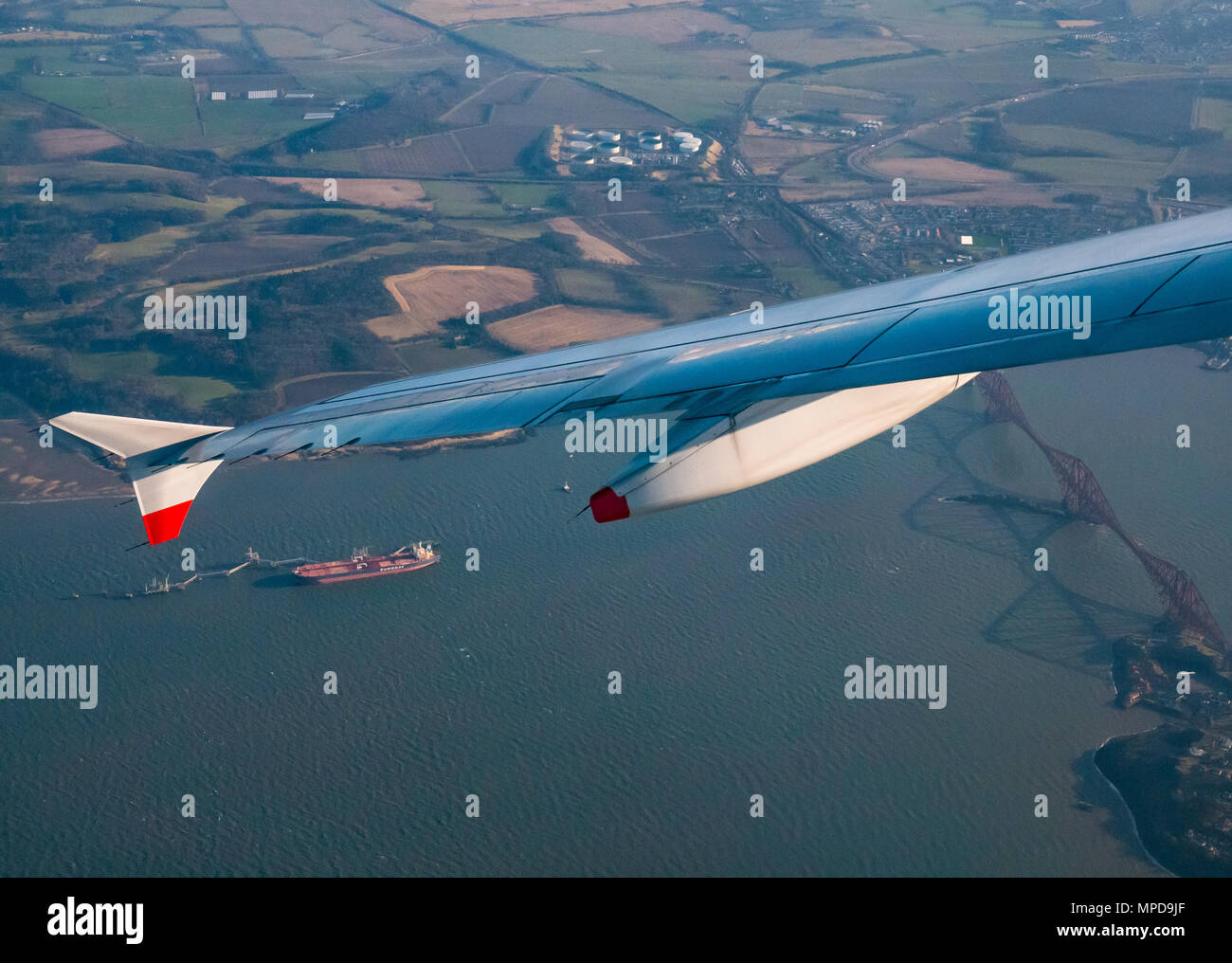 British Airways Airbus 319 tilted plane wing seen from plane window after take off from Edinburgh airport above Forth Rail Bridge with oil tanker Stock Photo