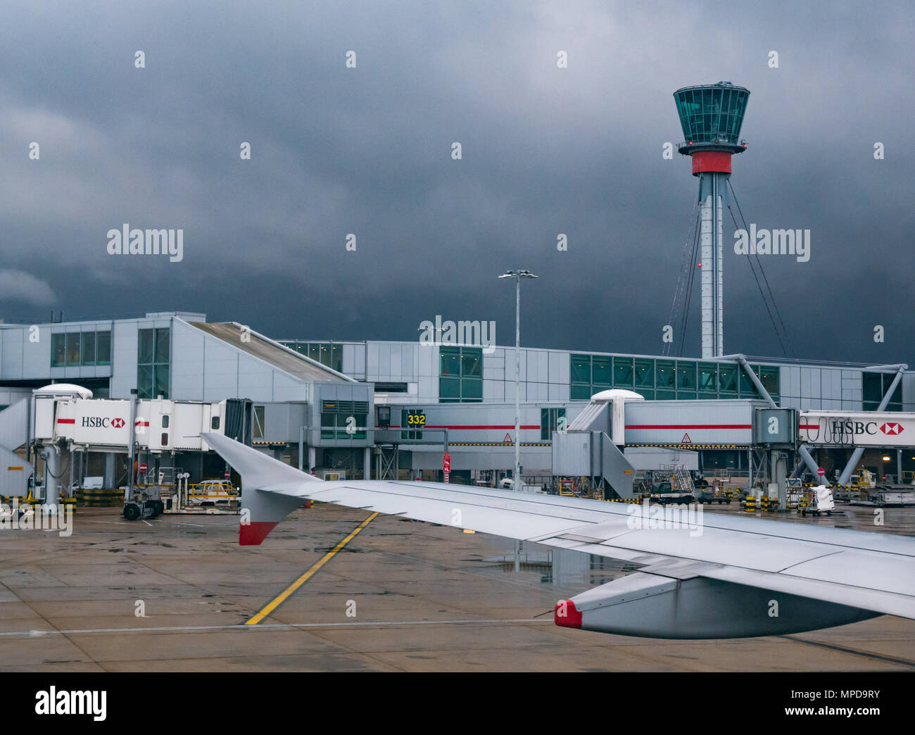View of sky bridges, Terminal 5, Heathrow airport, London, England, UK, taken from plane window, with plane wing and control tower visible. Stock Photo