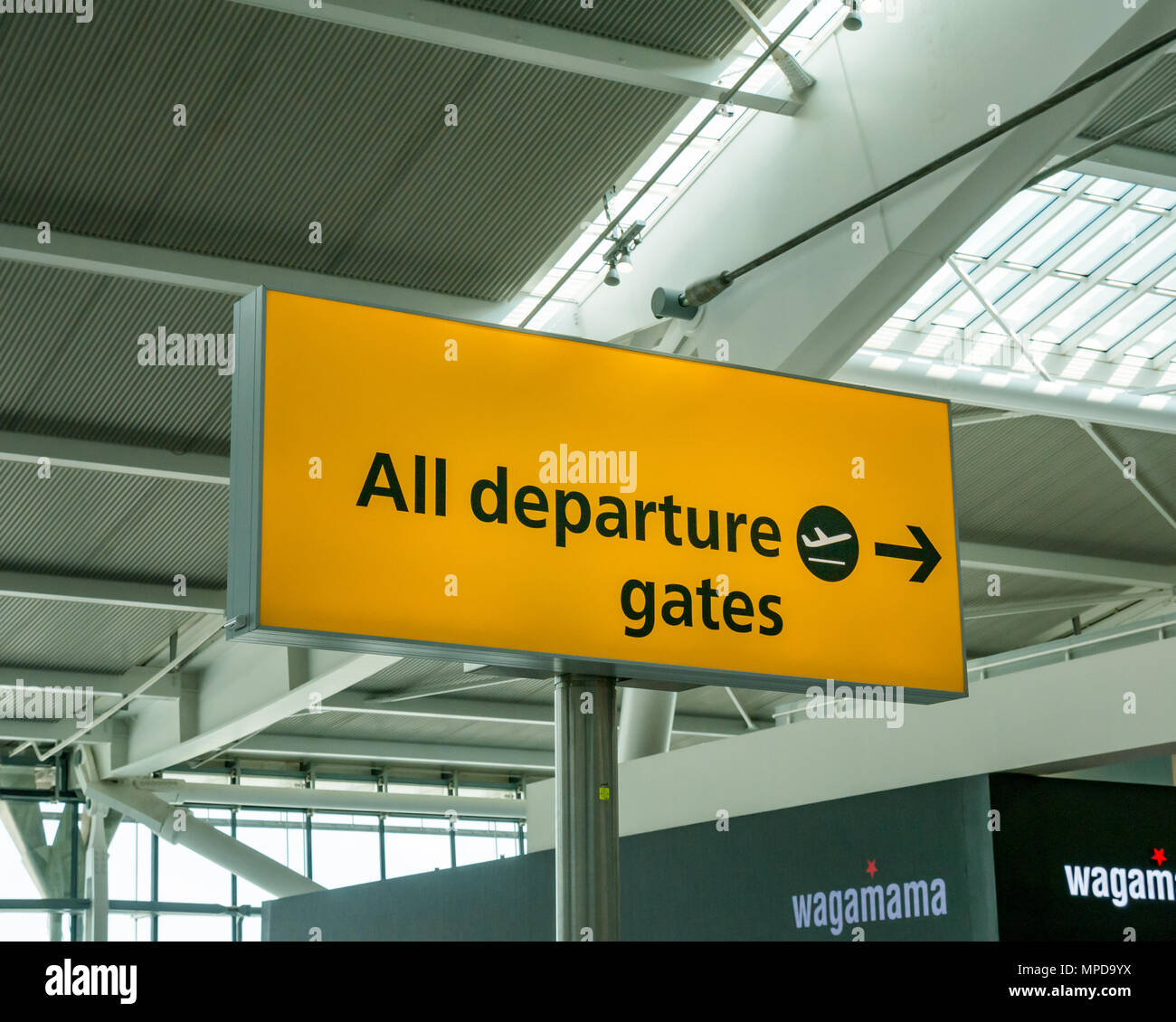Departure gates directional yellow sign, Terminal 5, Heathrow airport, London, England, UK Stock Photo