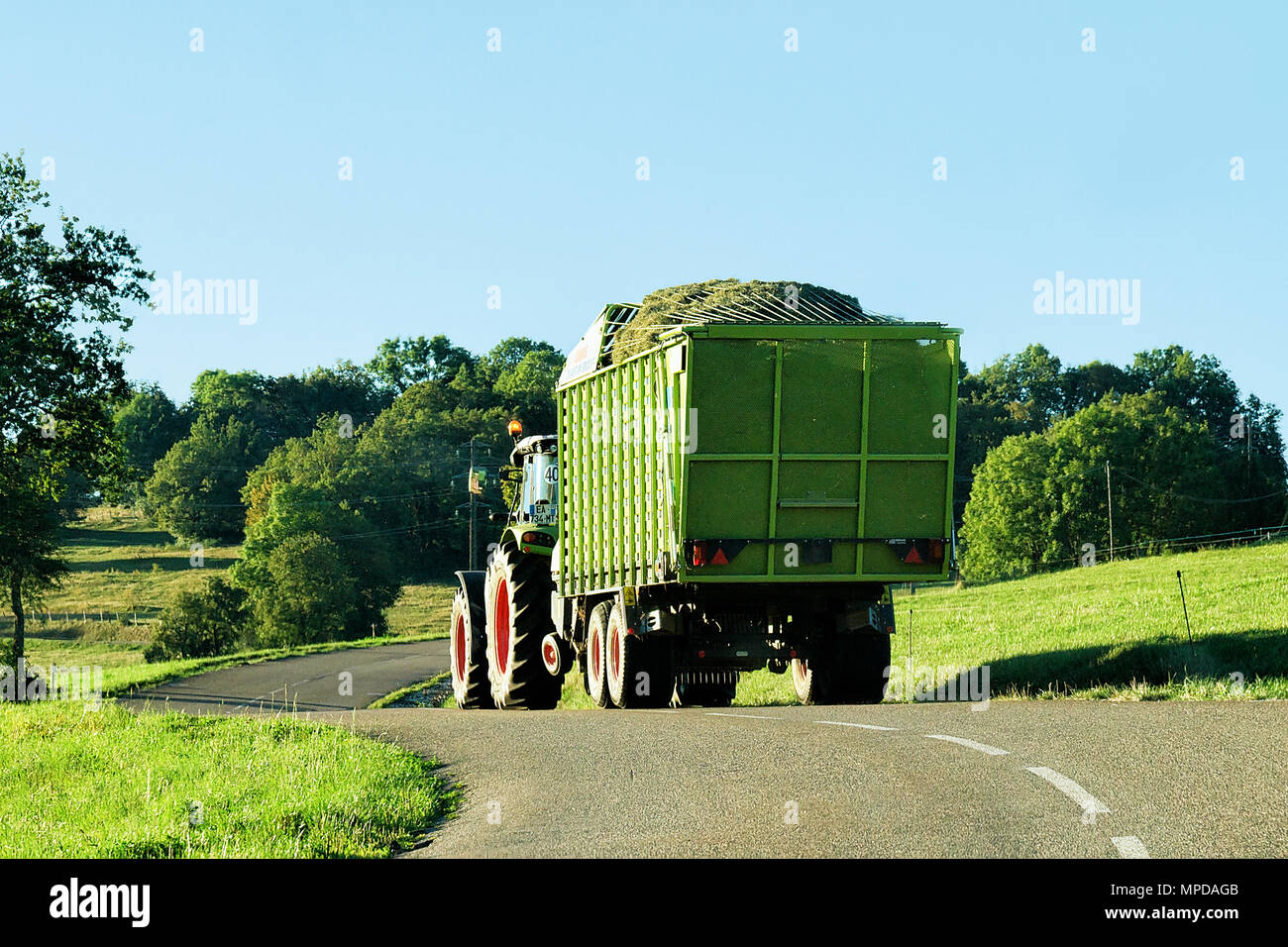 Ouhans, France - August, 25, 2016: Tractor with trailer full of hay on the road in Bourgogne-Franche-Comte region, France. Stock Photo